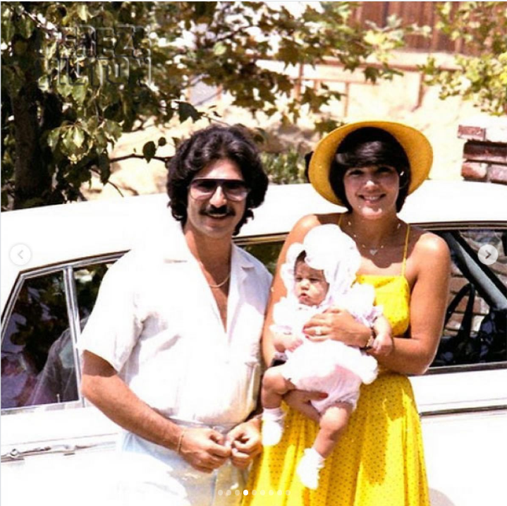 Kris Jenner poses with her husband and their baby daughter Kourtney in a sunny family snapshot, with the young mother wearing a yellow dress and wide-brimmed hat. | Source: Instagram/krisjenner