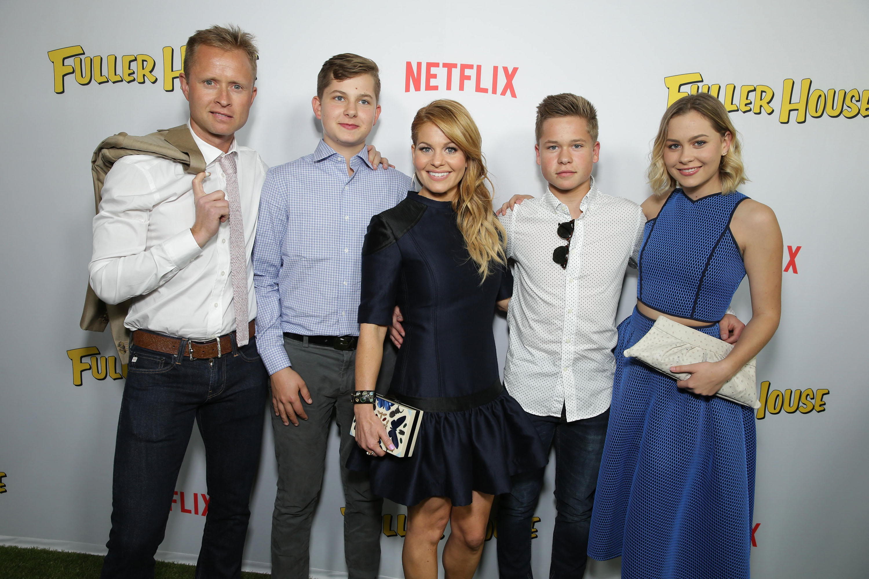 Candace Cameron Bure celebrates the premiere of Netflix's "Fuller House" alongside husband Valeri Bure and their children—Lev, Maksim, and Natasha—at The Grove in Los Angeles on February 16, 2016. The actress dazzles in a tailored navy mini dress featuring leather shoulder accents and a flouncy hemline, posing arm in arm with younger son Maksim, who looks sharp in a white dotted button-down shirt and dark denim. | Source: Getty Images