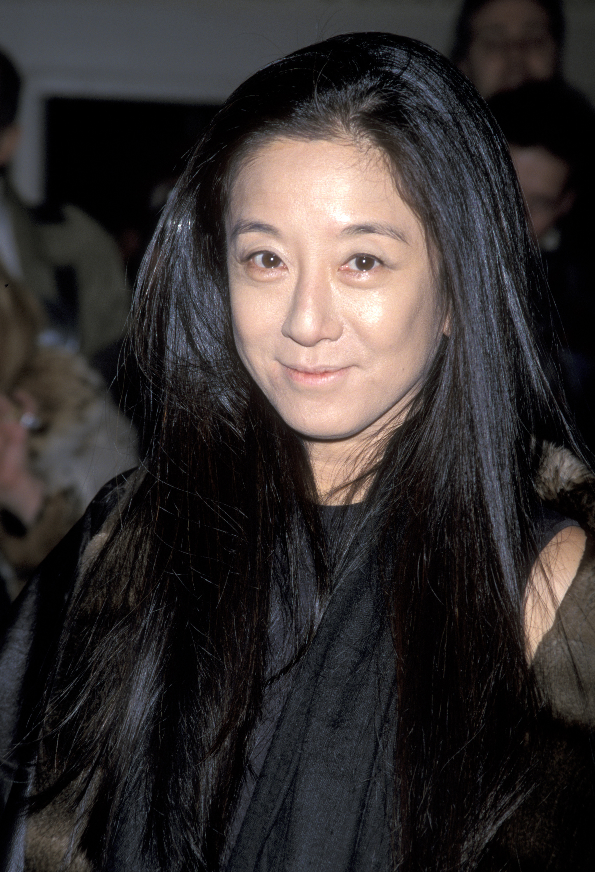 Vera Wang smiled for a close-up portrait while attending the 40th Anniversary Celebration of the Barbie Doll at the Waldorf-Astoria Hotel on February 7, 1999, in New York City. The renowned fashion designer opted for a minimalist black ensemble layered with a scarf and fur-trimmed outerwear, styling her raven hair straight and loose around her shoulders. | Source: Getty Images