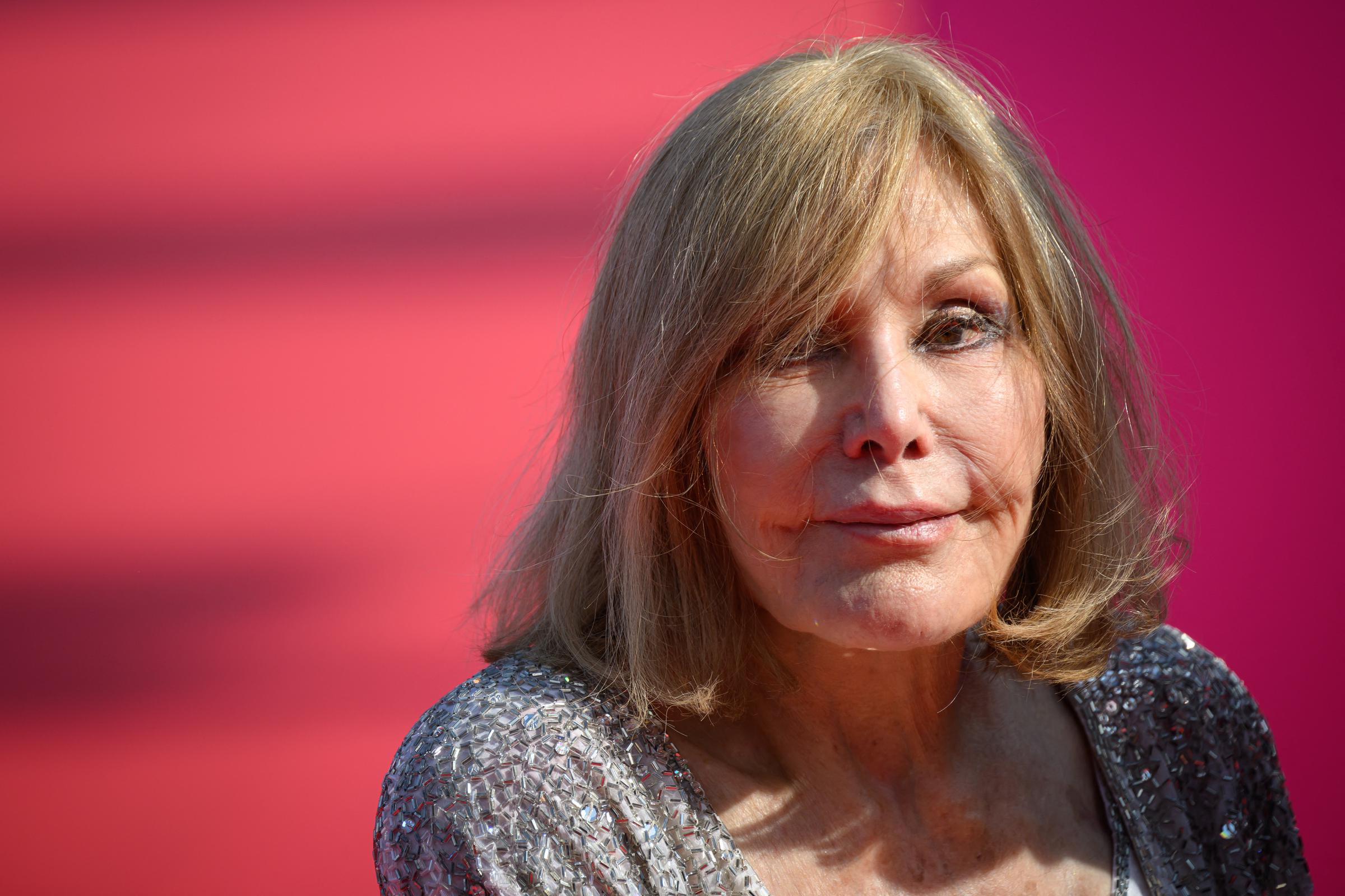 Kim Novak poses for a close-up portrait at the 51st Deauville American Film Festival on September 6, 2025, wearing a shimmering silver outfit with a deep neckline. Her shoulder-length blonde hair frames her face against a pink-and-red background. | Source: Getty Images