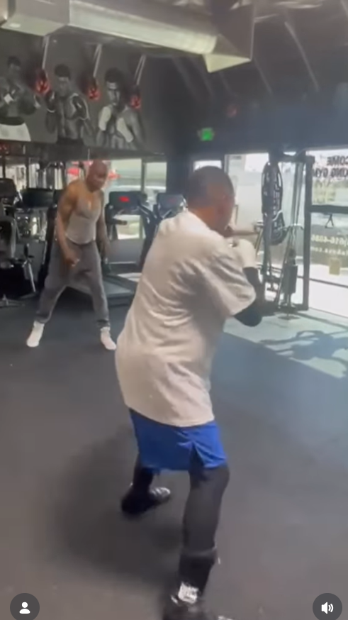 Martin Lawrence begins working through his moves, stepping forward with focused footwork while another man behind him mirrors the routine near the gym floor. | Source: Instagram/martinlawrence
