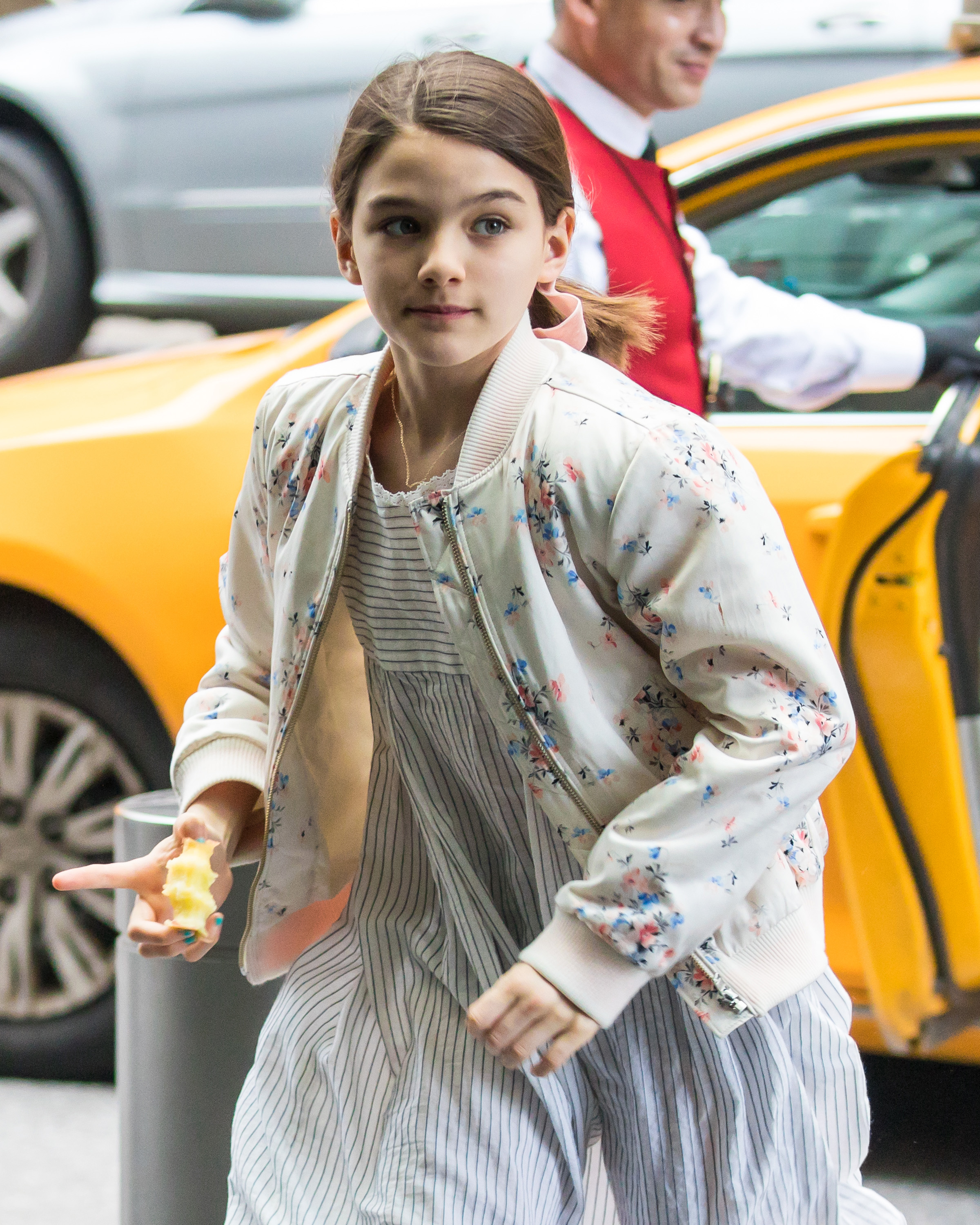 Young Suri Cruise is spotted stepping out of a cab, clutching an unfinished apple in one hand—a small, candid detail that adds a touch of everyday life to the scene. With her youthful curiosity on full display, the image captures a fleeting moment of simplicity amid the city’s fast pace.