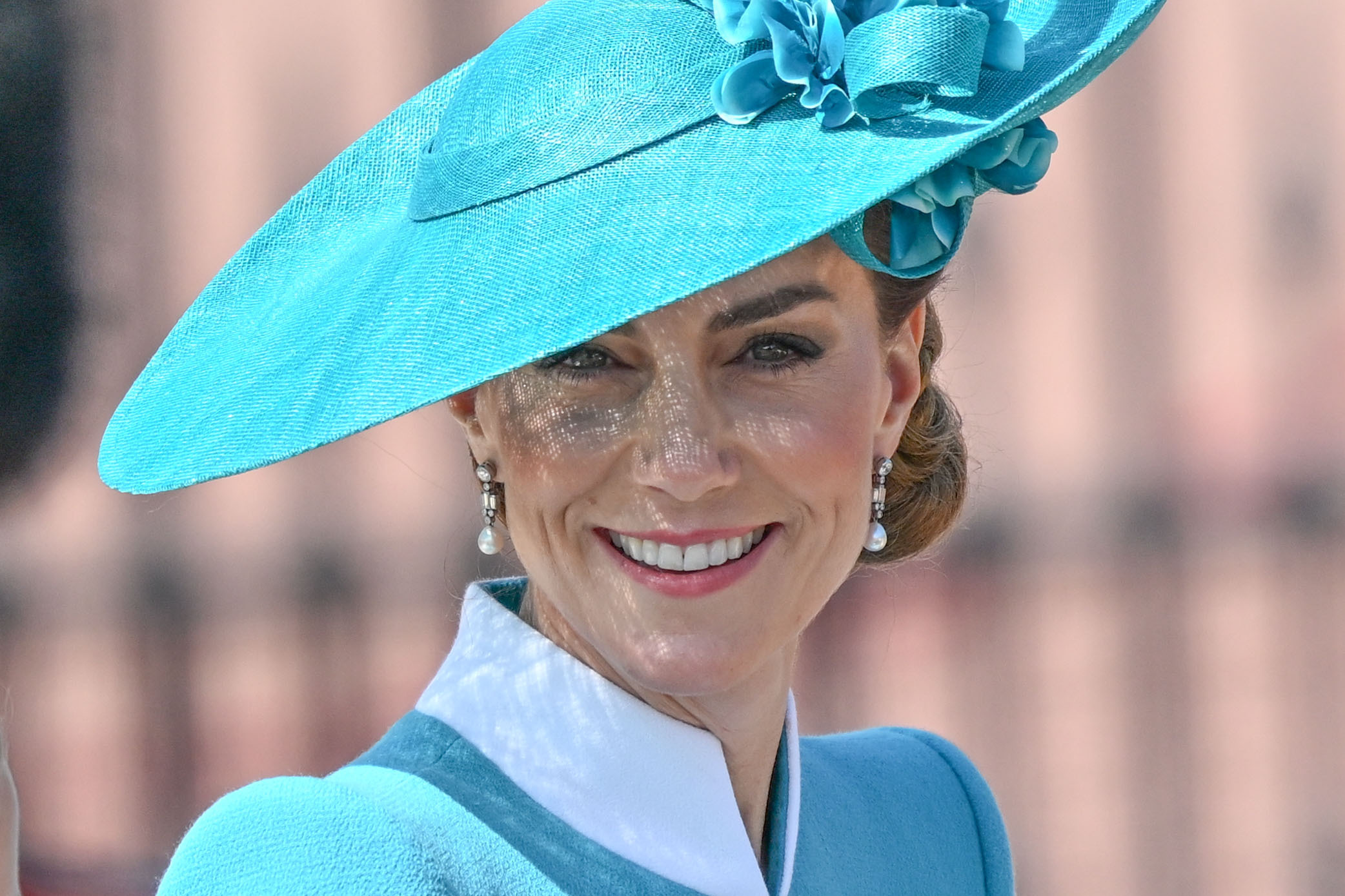 In a close-up taken during the 2025 Trooping the Colour parade, Princess Catherine beams with a warm smile. The photo captures her face in radiant detail, framed by an elegant teal hat adorned with floral embellishments—an image of grace and confidence at the heart of the royal celebration.