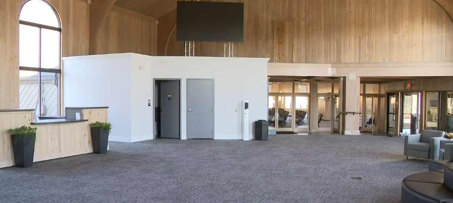 Another section of the renovated interior combined pale wood paneling with carpeting, modern seating, and newly constructed rooms beneath the mansion's high ceiling. Large glass doors connected this open gathering area with neighboring spaces, illustrating how Living Word Sanctuary Church divided portions of Mike Tyson's enormous former residence into practical areas capable of serving members beyond regular worship services and gatherings. | Source: YouTube/WKYC Channel 3