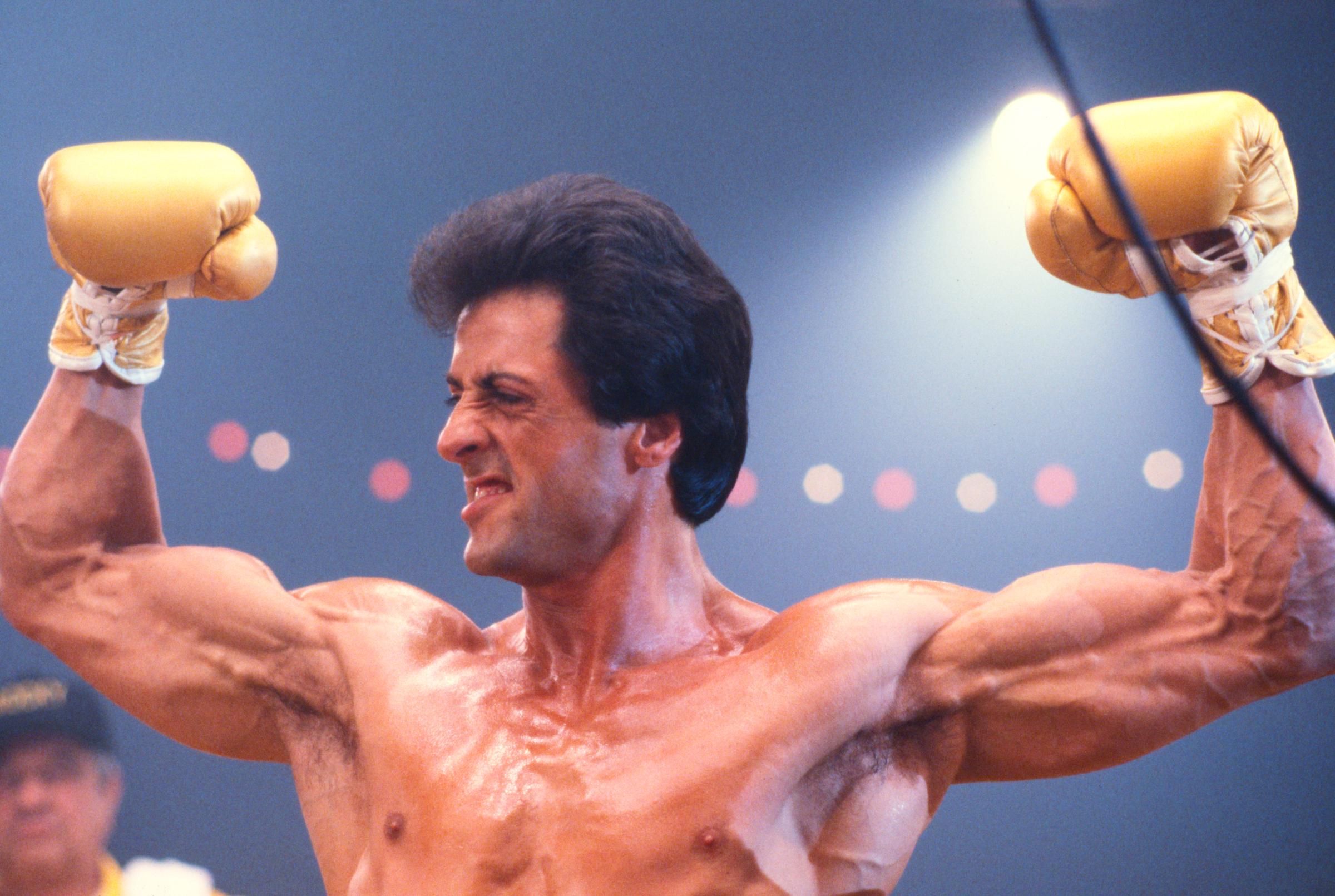 Sylvester Stallone, as Rocky Balboa, flexes both arms in the boxing ring on the set of "Rocky III" in Los Angeles, California, in May 1982. The close-up offers a striking view of Stallone's muscular definition and vascularity after he pushed his training and diet to extremes while preparing for the third installment.