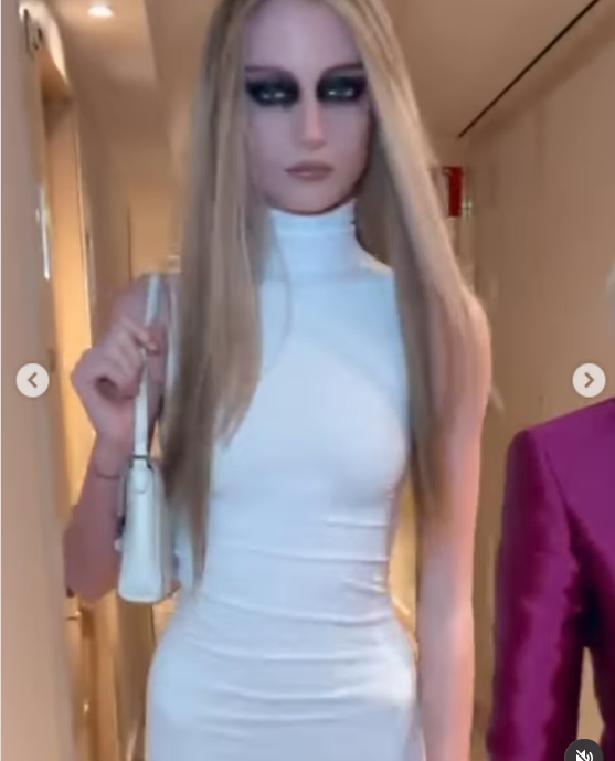 Kai Schreiber walked briskly down an indoor corridor en route to the Gucci show during Milan Fashion Week. The model looked captivating in a sleeveless white turtleneck minidress with a matching structured shoulder bag, accentuated by sleek, pin-straight blonde hair and intense, heavily smudged dark eye makeup. | Source: Instagram/kaischreiberrr