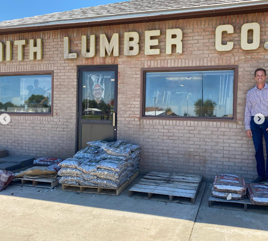 Outside a lumber company, Bryon stands off to the side—quiet, everyday America captured in brick, pallets, and sun. | Source: Instagram/sdbryonnoem