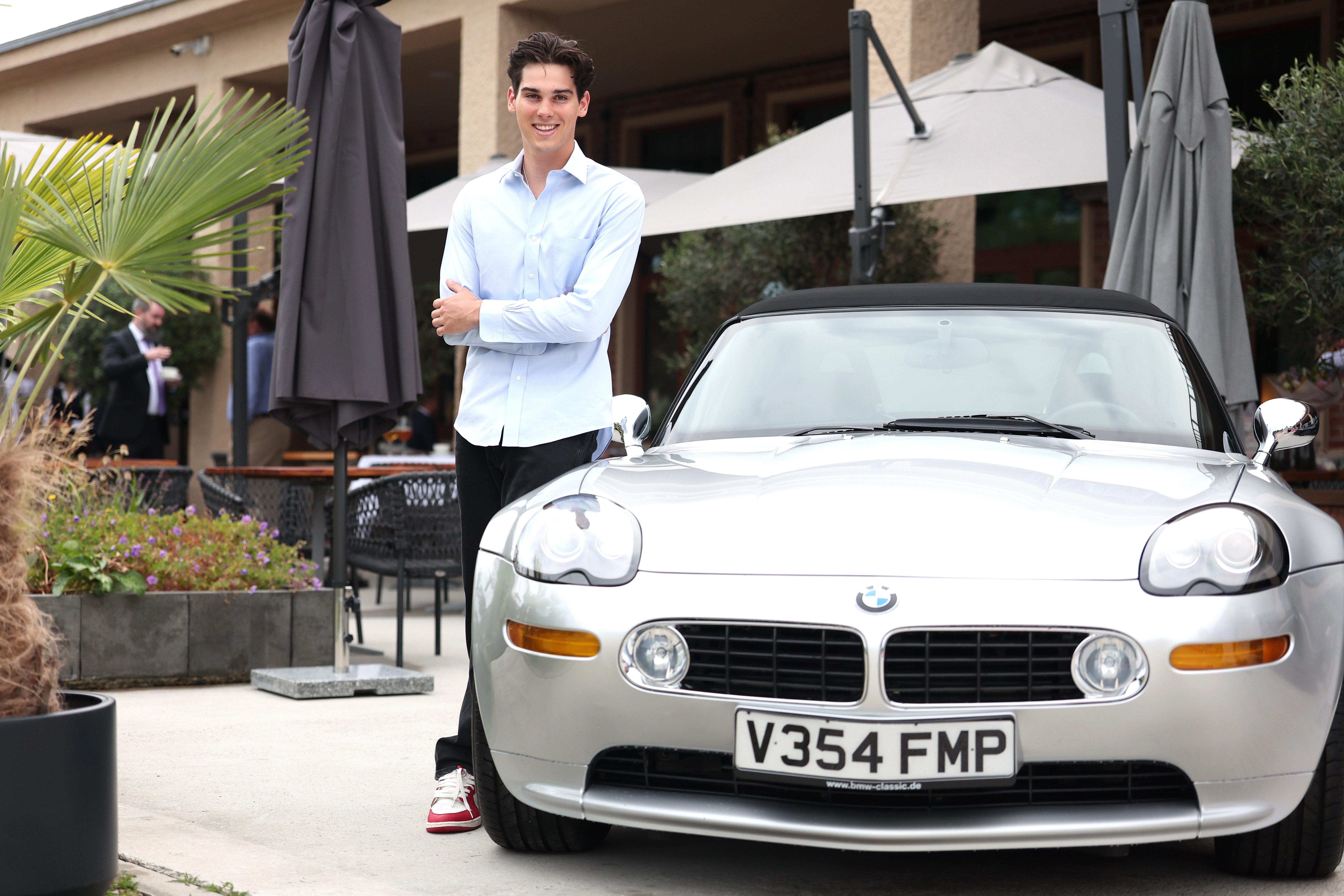 Paris Brosnan with the BMW Z8, which his father Pierce Brosnan drove during the James Bond 007 "The World Is Not Enough" film from 1999, on July 15, 2025 in Munich, Germany | Source: Getty Images