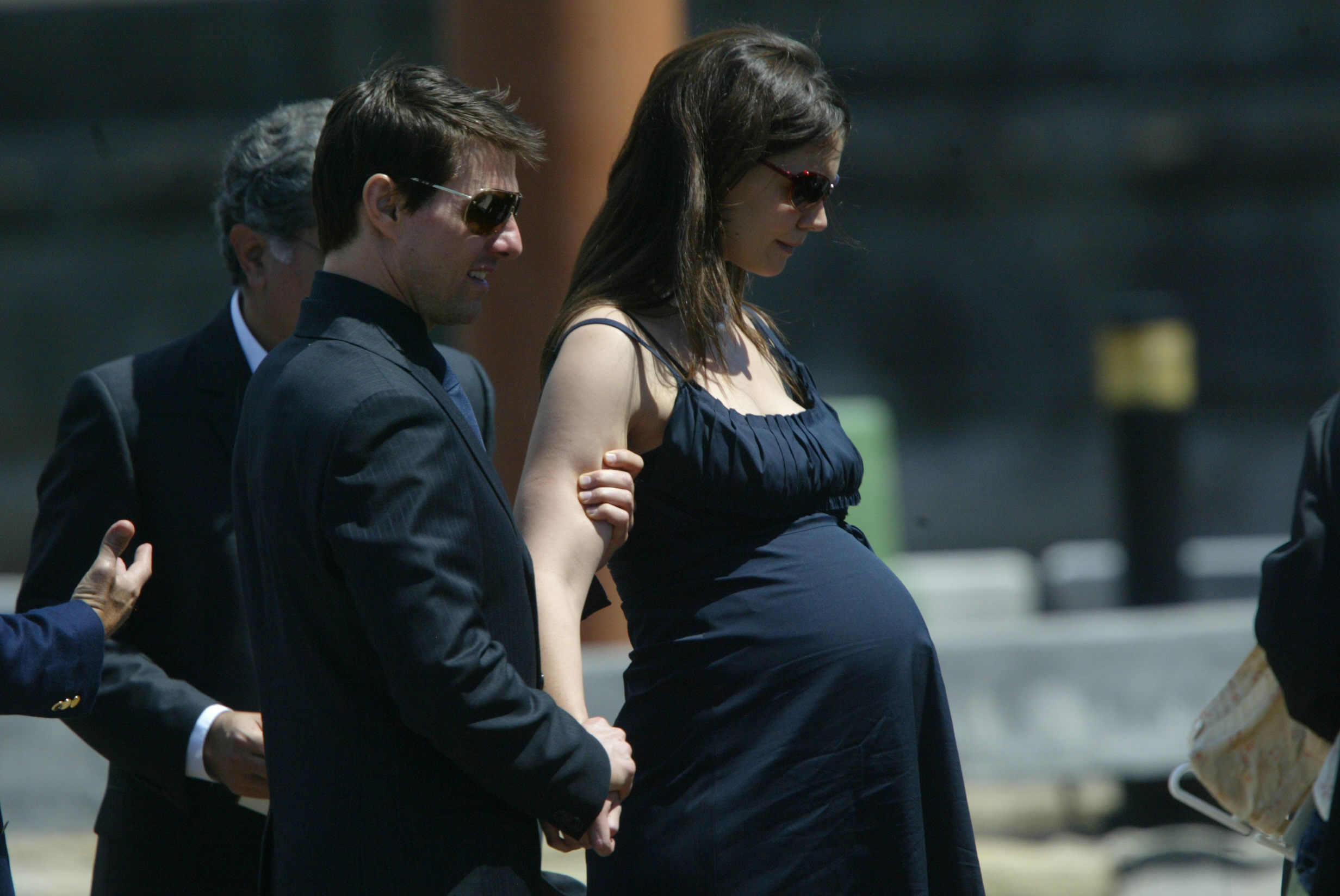 In a serene moment, a visibly pregnant Katie Holmes walked arm-in-arm with Tom Cruise, radiating calm elegance in a navy blue dress and dark sunglasses. The then-couple appeared composed and united, capturing a quiet, intimate moment during a public appearance.