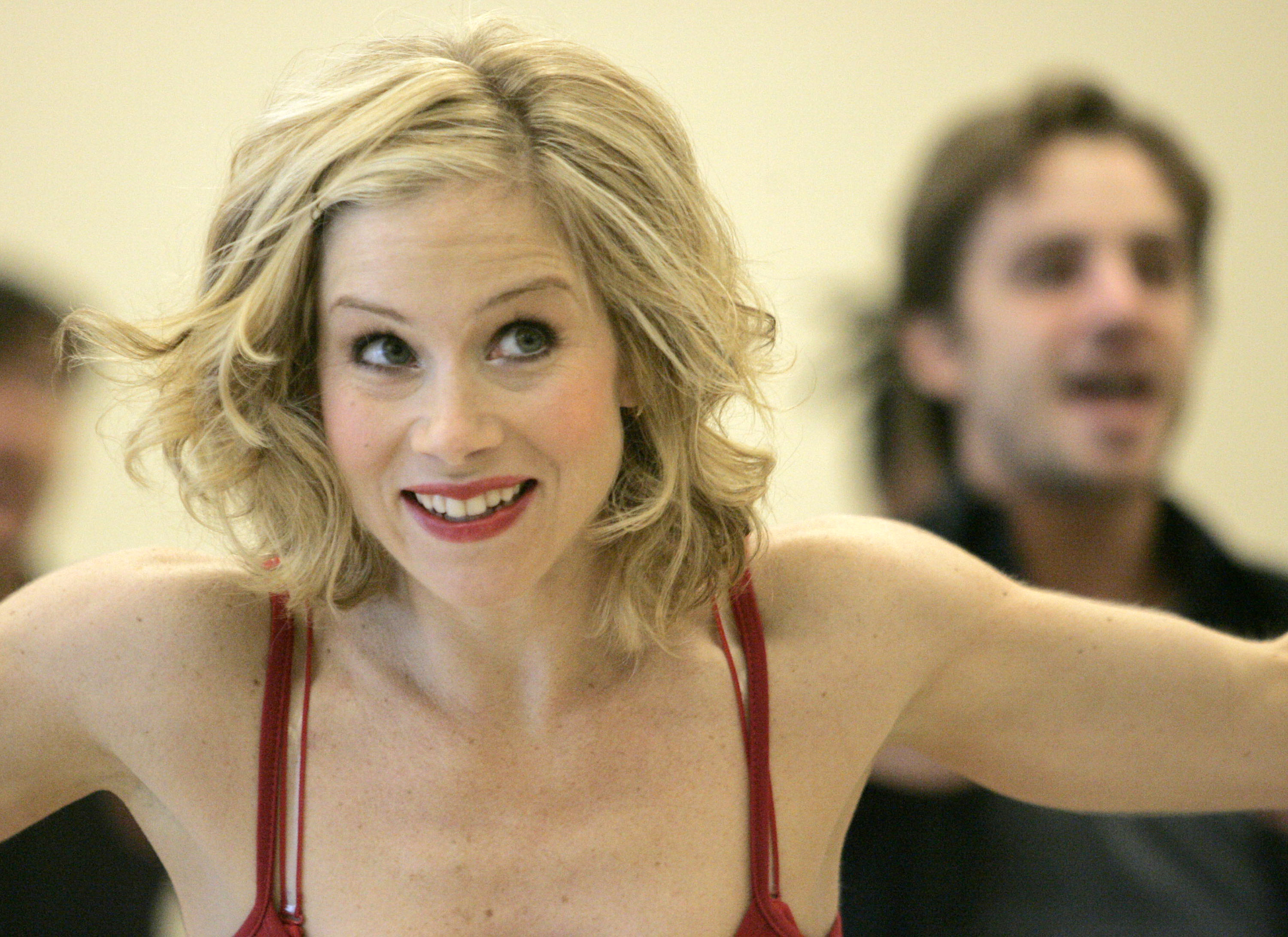 Christina Applegate flashed an energetic, wide smile mid-movement during rehearsals for the Broadway musical "Sweet Charity" on January 19, 2005, in New York City. The performer showcased a tousled, wavy blonde bob and berry-toned lipstick, rehearsing choreography in a red strappy camisole alongside fellow ensemble members. | Source: Getty Images