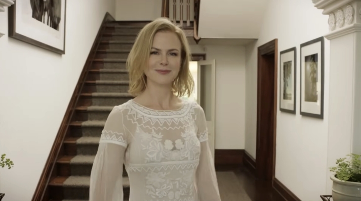 Inside the entry hall, detailed wood trim and a carpeted staircase add warmth and depth to the farmhouse interior, where high ceilings and framed artwork create a refined country aesthetic. From a video dated July 20, 2015. | Source: YouTube/Vogue