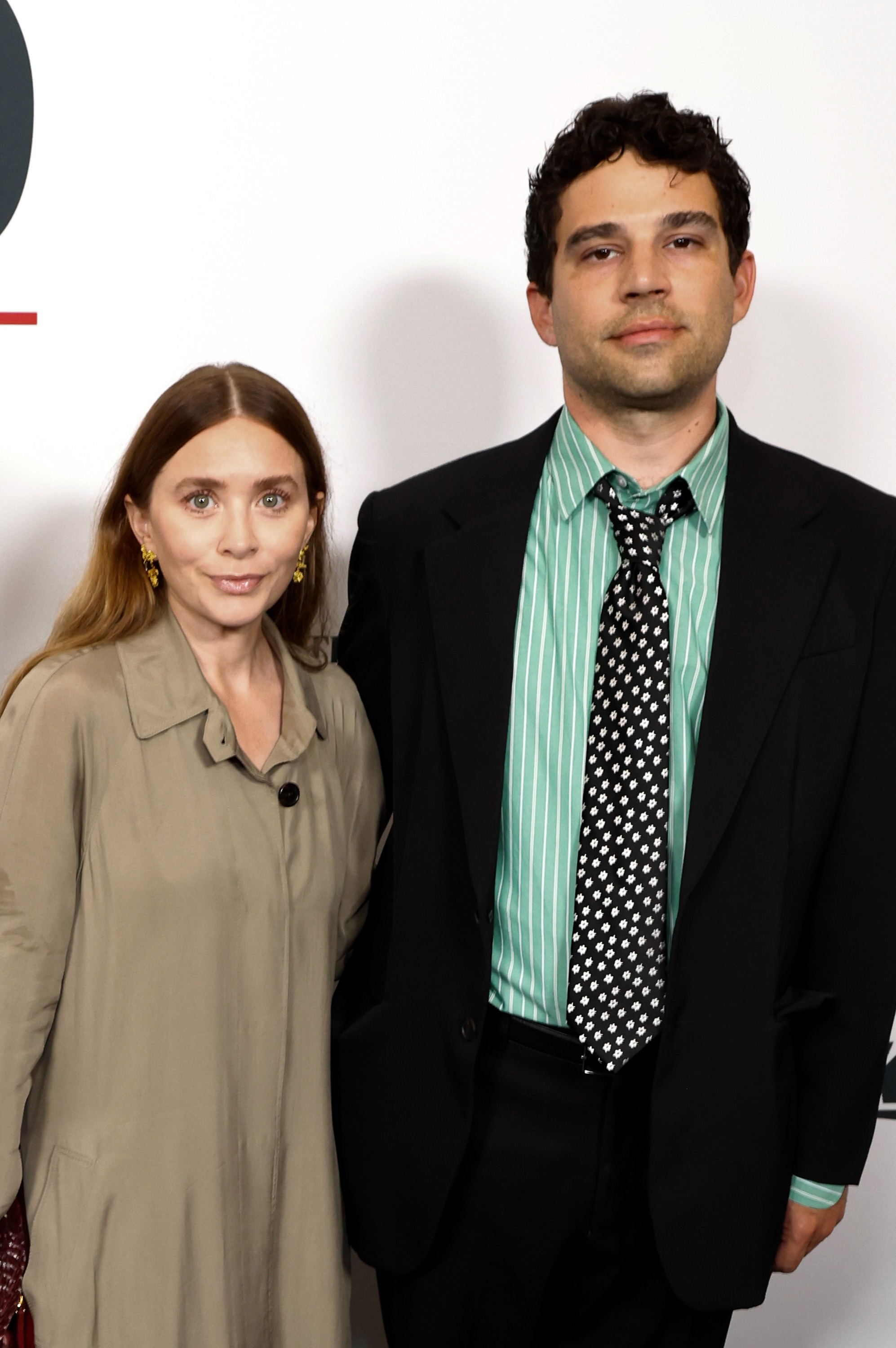 Soft, smooth skin, a gentle smile, and soft center-parted brown hair framed the face of 39-year-old Ashley Olsen at the YES Scholars Gala on September 4, 2025, where she wore a muted beige-khaki trench coat paired with small, statement drop earrings.