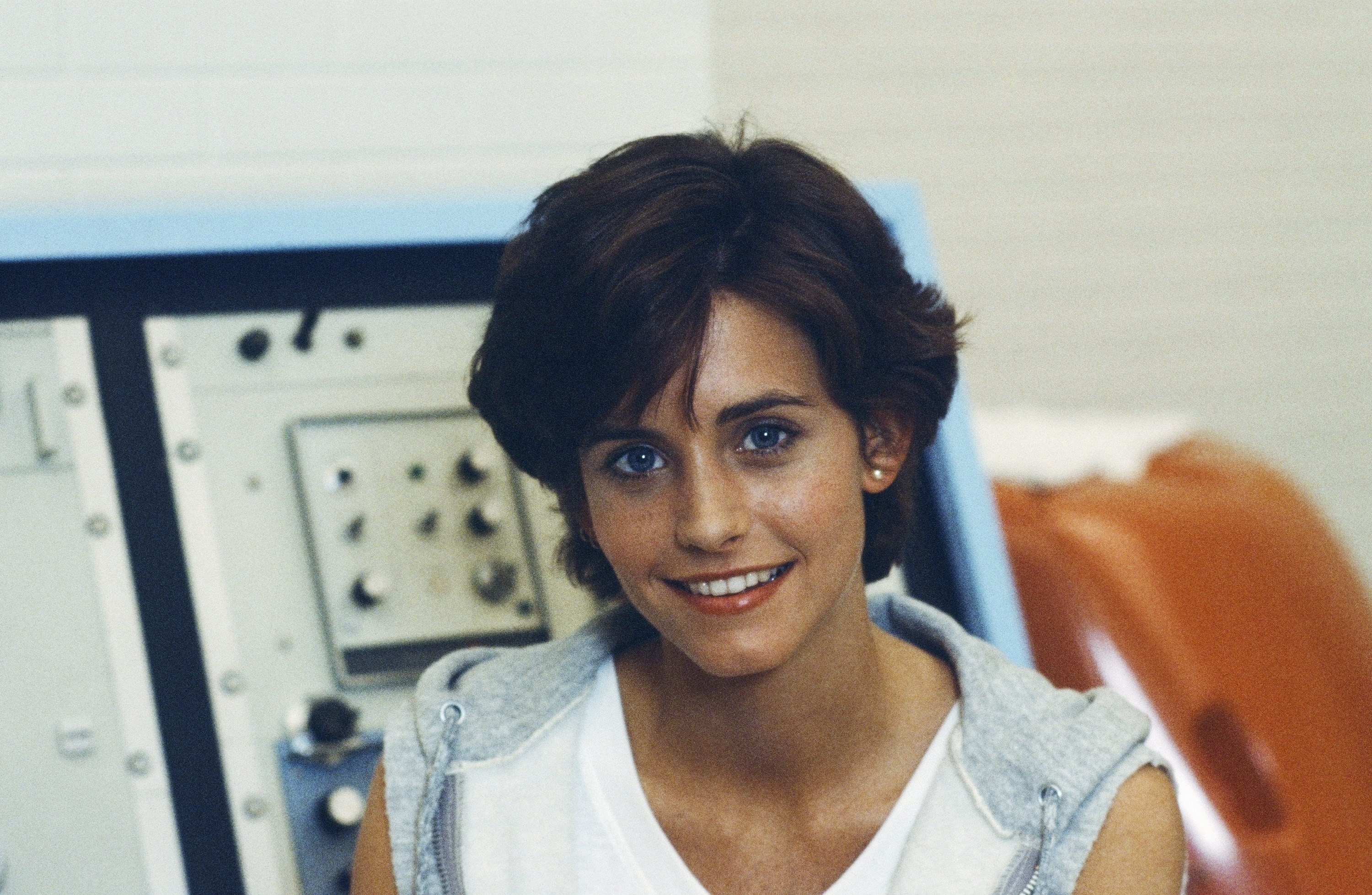 A young Courteney Cox flahses a faint smile at the camera on the set of "Misfits of Science," where she starred as Gloria Dinallo.