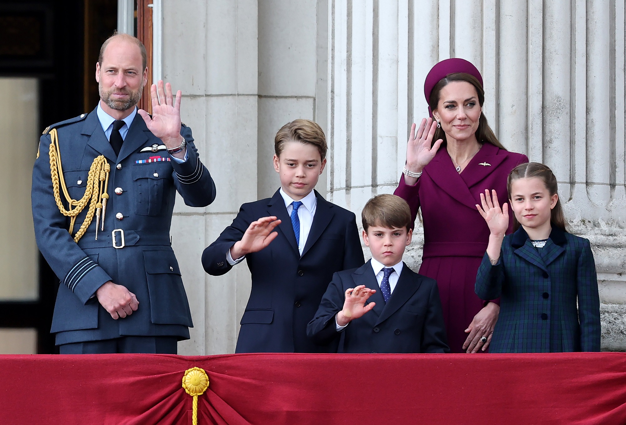 Prince William joins Catherine, Princess of Wales, and their children on the balcony during the VE Day 80th anniversary. William wears a formal Royal Air Force uniform while the entire family waves at the crowd.