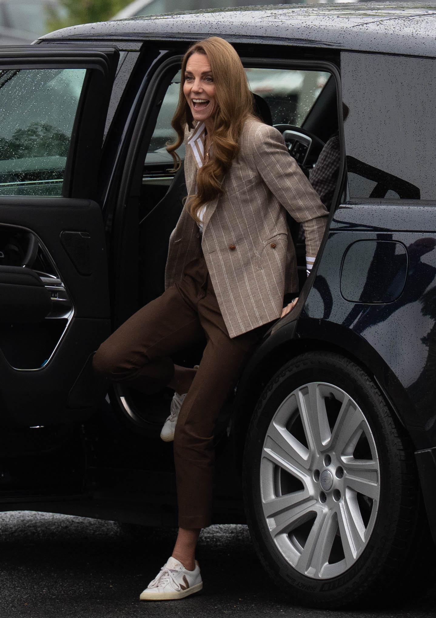Princess Catherine steps out of a black SUV under overcast skies for her Colchester Hospital visit. Dressed in earth-toned pants, sneakers, and a pinstripe blazer, she arrives ready to dig in — literally and figuratively.