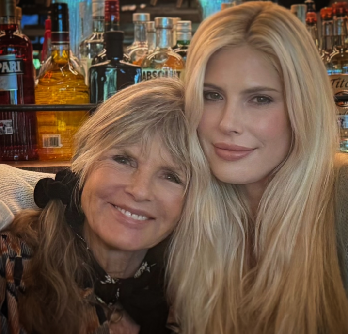 In a sweet mother-daughter selfie shared to Instagram on November 21, 2025, Cleo Rose Elliott posed cheek-to-cheek with her mother, Katharine Ross, while enjoying an outing together. The duo smiled warmly against a vibrant bar backdrop, with Katharine wearing an patterned top paired with a black neckerchief and dark scrunchie, while Cleo showcased long, center-parted blonde waves and soft, glowing makeup. | Source: Instagram/cleoroseelliott