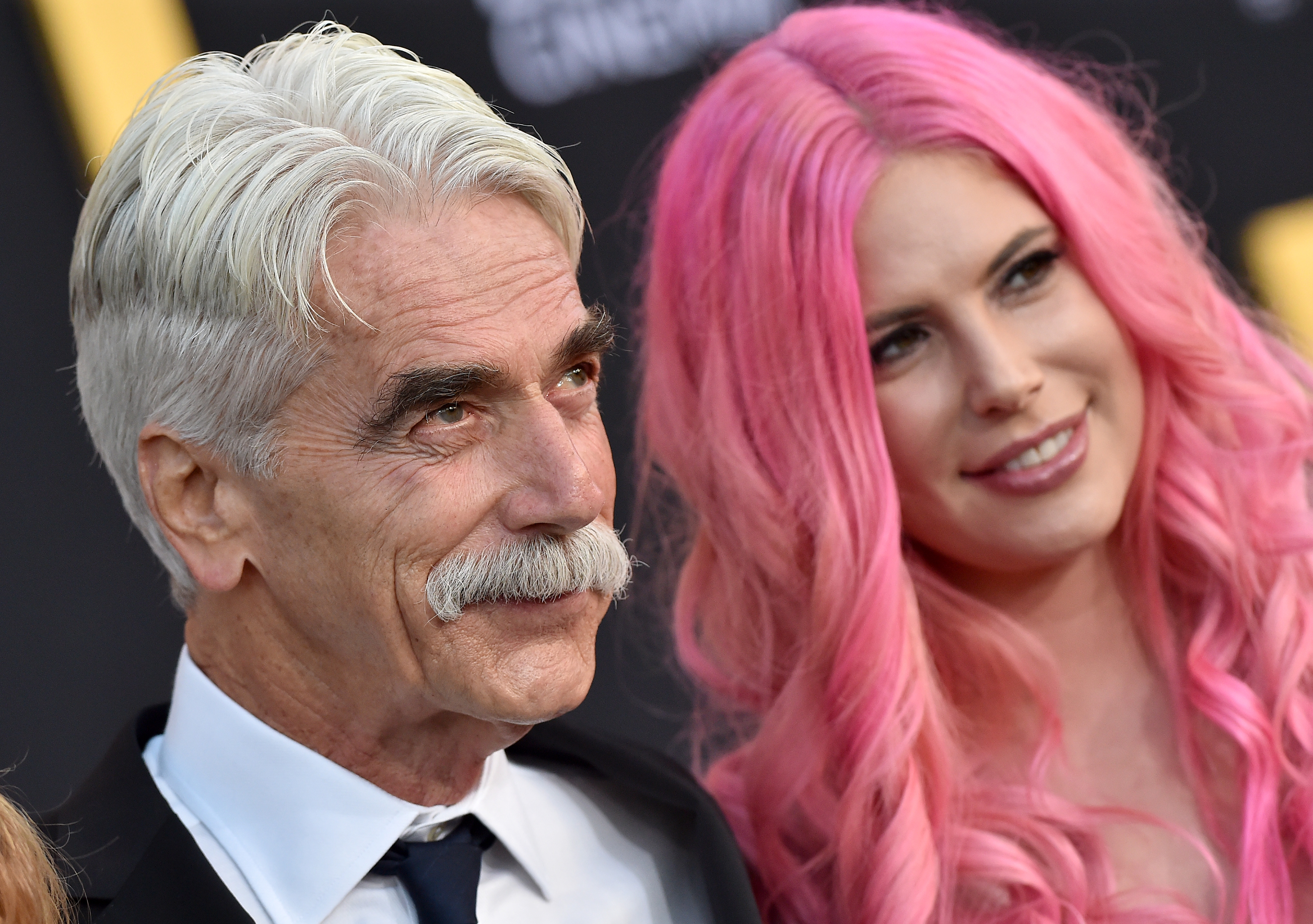 Sam Elliott and daughter Cleo Rose Elliott stood side-by-side at the Los Angeles premiere of "A Star Is Born" at The Shrine Auditorium on September 24, 2018. The veteran actor looked dapper in a tailored dark suit, crisp white shirt, and tie, sporting a slicked-back hairstyle and his iconic silver mustache, while Cleo turned heads with vibrant, bubblegum-pink wavy tresses and a radiant smile.