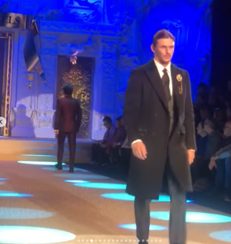 Jake Hall walks the runway in a black suit and long coat during a fashion show. | Source: Instagram/jakehall