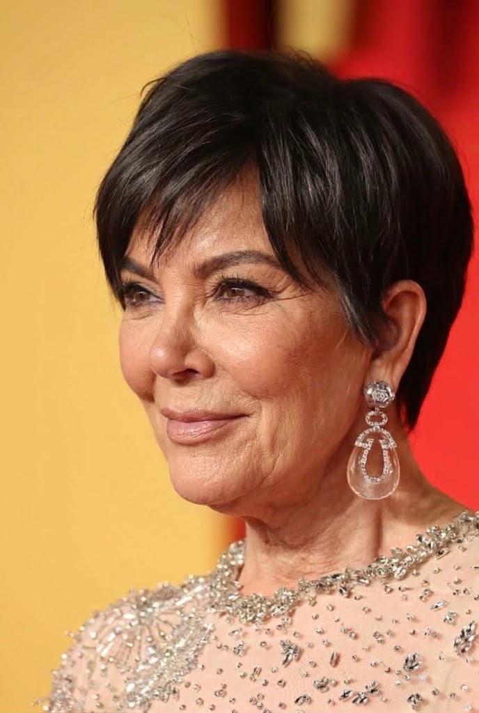 In this profile view, gray strands and softly defined facial lines create a more naturally aged version of Kris beneath the dazzling earrings. | Source: Gemini