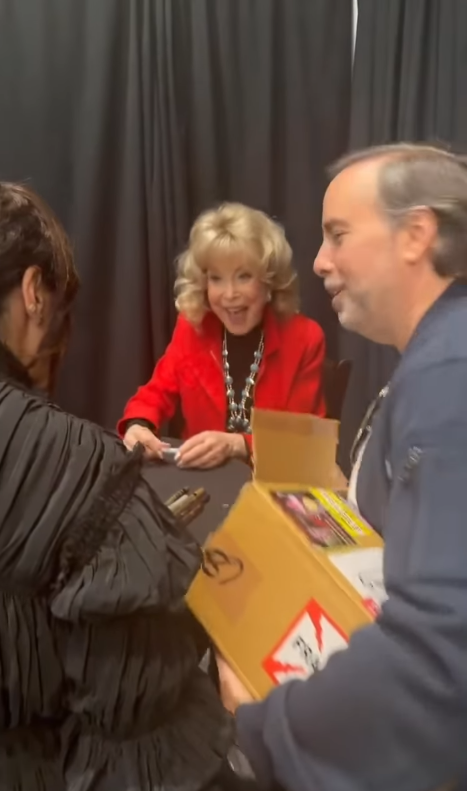Barbara Eden smiles in a vibrant red outfit and statement necklace as she meets fans and signs memorabilia at The Hollywood Show in Los Angeles. | Source: Instagram/hollywoodshow1