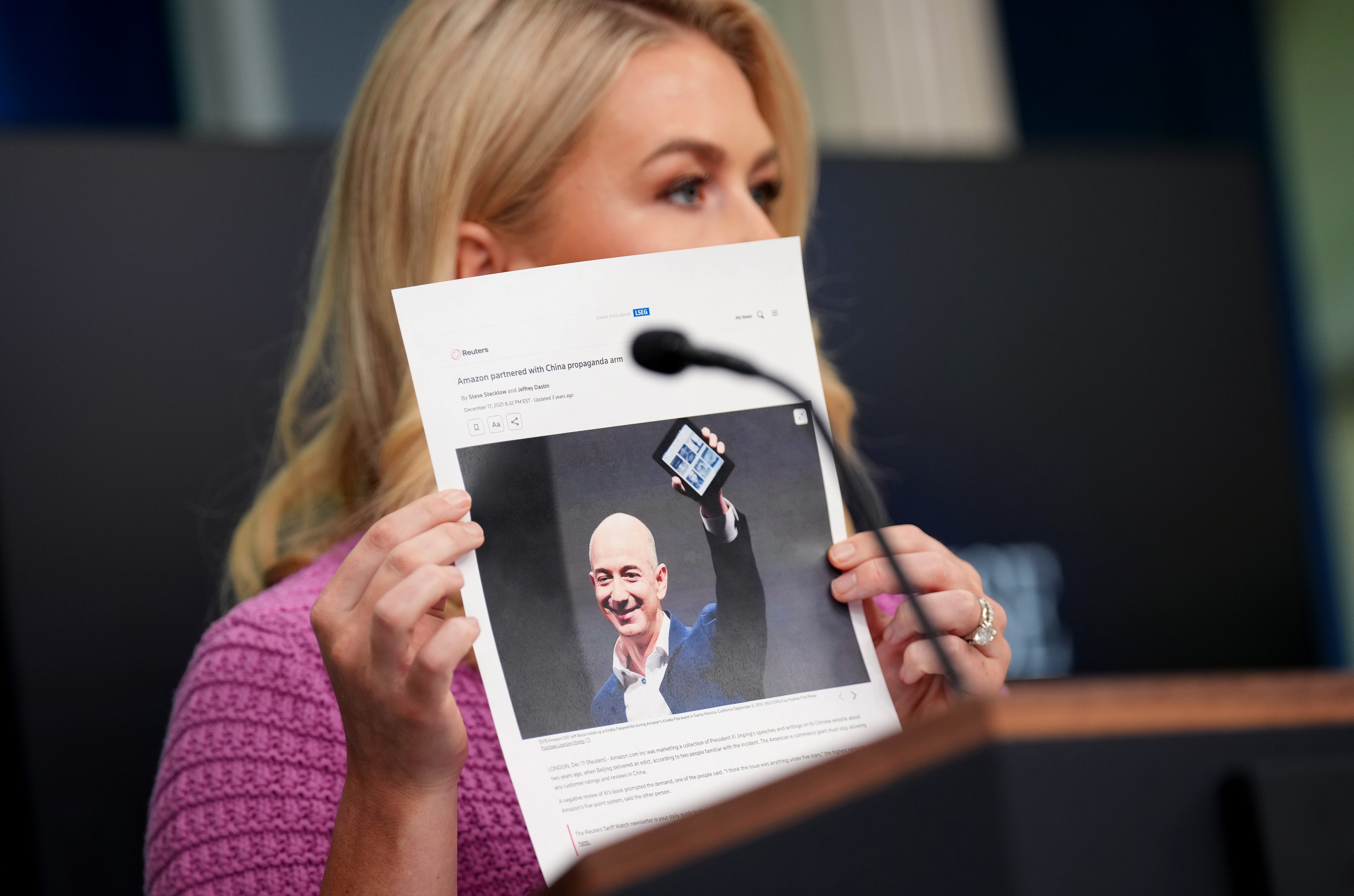 Karoline Leavitt holding up a paper showing a Reuters article excerpt about Jeff Bezos and Amazon. | Source: Getty Images
