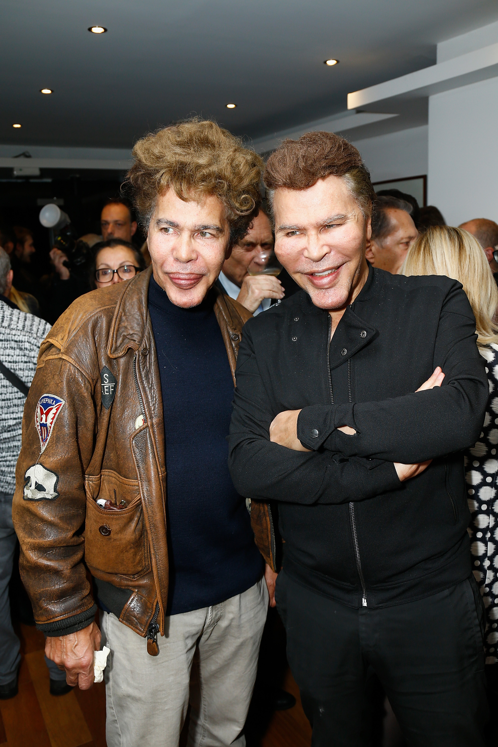 Igor and Grichka Bogdanov attend "Les Fantômes De La Rue" at Theatre La Bruyère in Paris, France. The changes in their faces are striking, with noticeably fuller lips, altered cheeks, and a different nose shape as they mingle with other attendees.