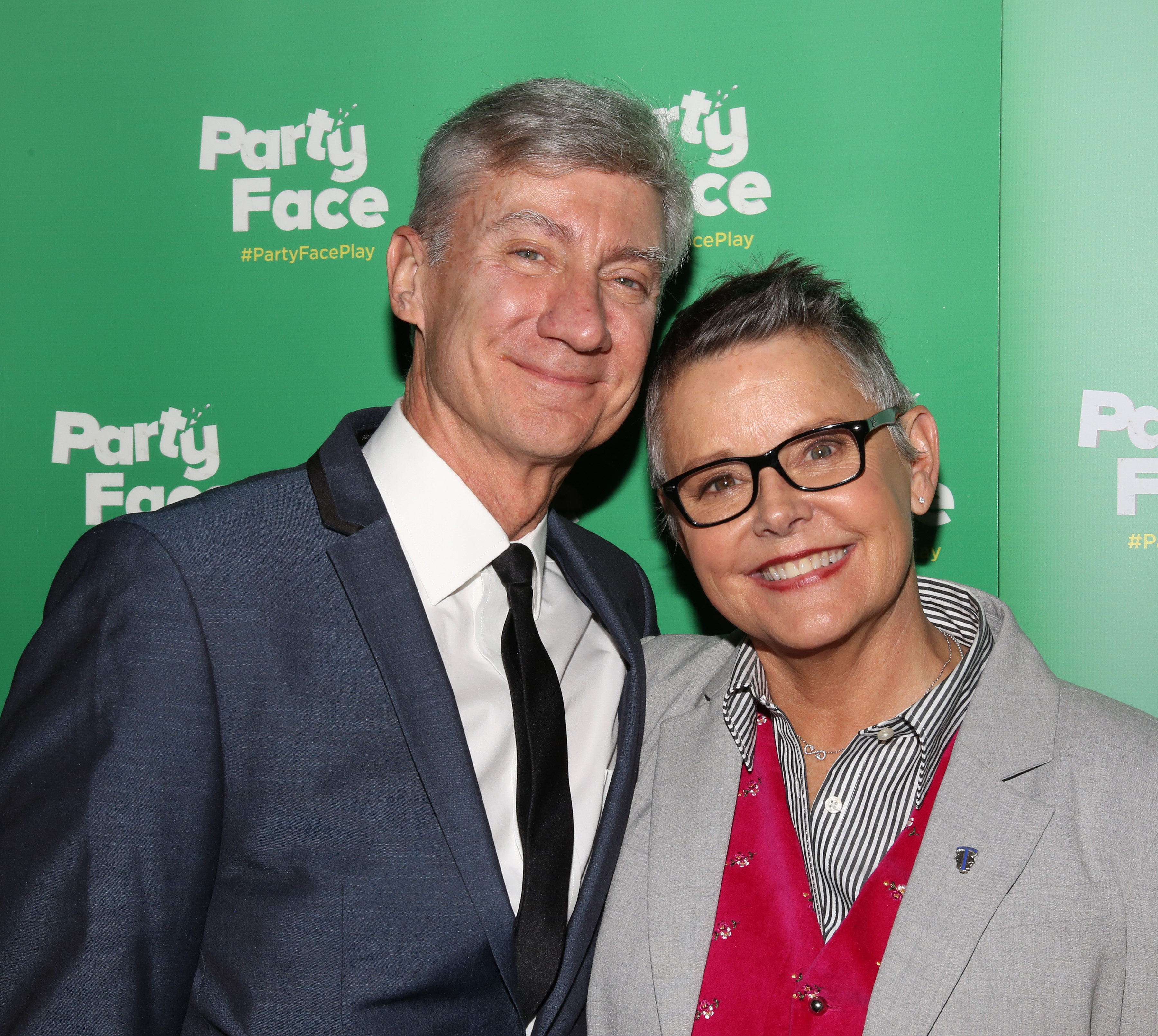 David Garrison and Amanda Bearse shared a warm reunion as they smiled together during the opening night of "Party Face" at Robert 2 Restaurant on January 22, 2018, in New York City. The former "Married... with Children" co-stars looked festive in front of the green photo backdrop, with Garrison dressed in a navy suit, crisp white dress shirt, and slim black tie, standing side by side with Bearse, who wore a tailored grey blazer over a bold pink velvet vest and striped collared shirt. | Source: Getty Images