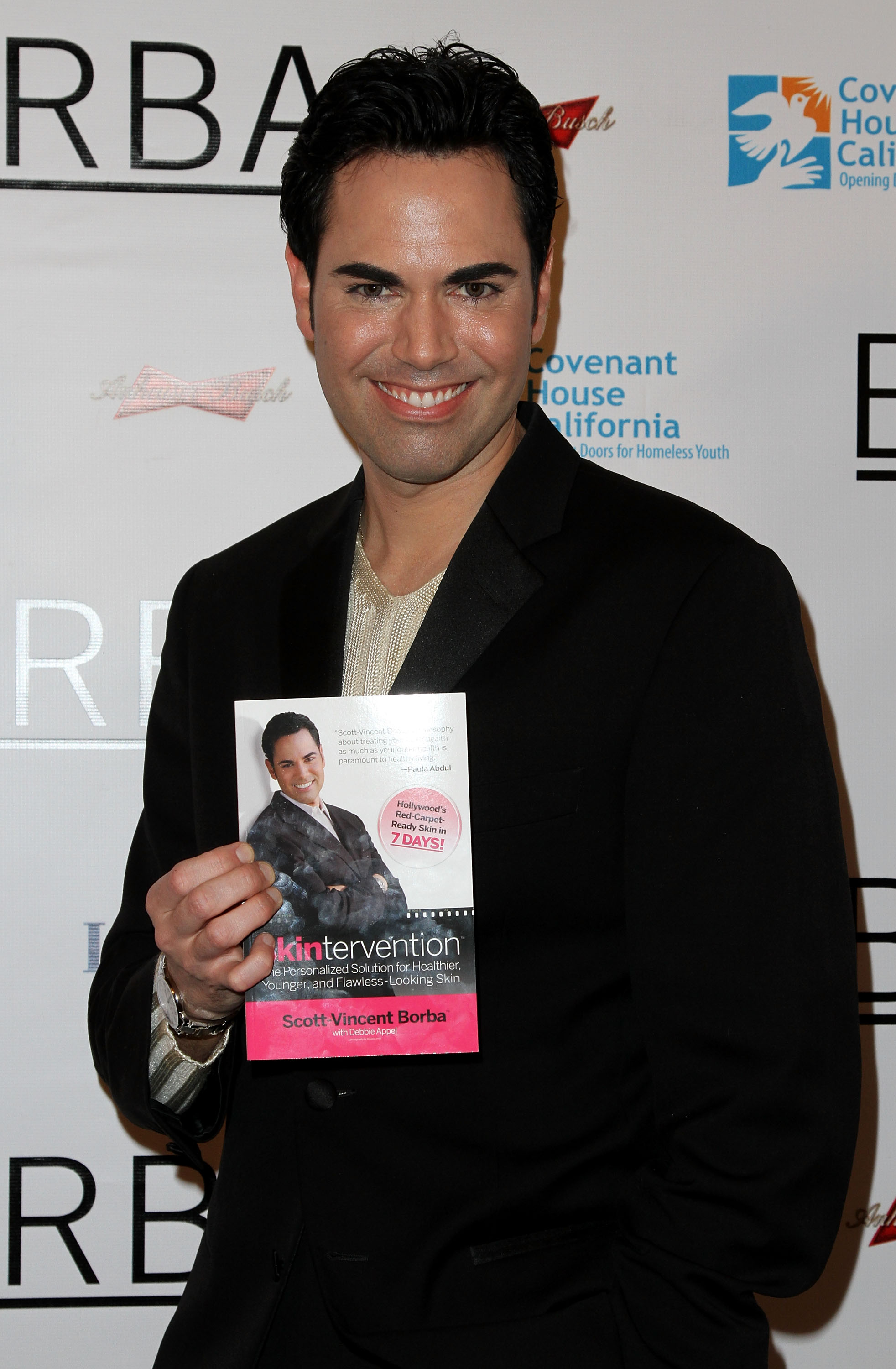 Scott Vincent Borba poses with his book Skintervention: The Personalized Solution for Healthier, Younger, and Flawless-Looking Skin during the height of his career in the beauty industry, years before leaving his Hollywood lifestyle to become a Catholic priest. | Source: Getty Images