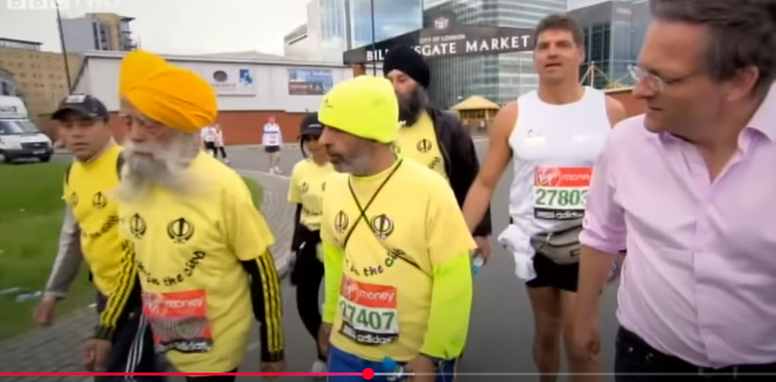 Fauja Singh (second from left) interviewed by BBC journalist during the London Marathon. From a video dated August 6, 2012. | Source: YouTube/BBC