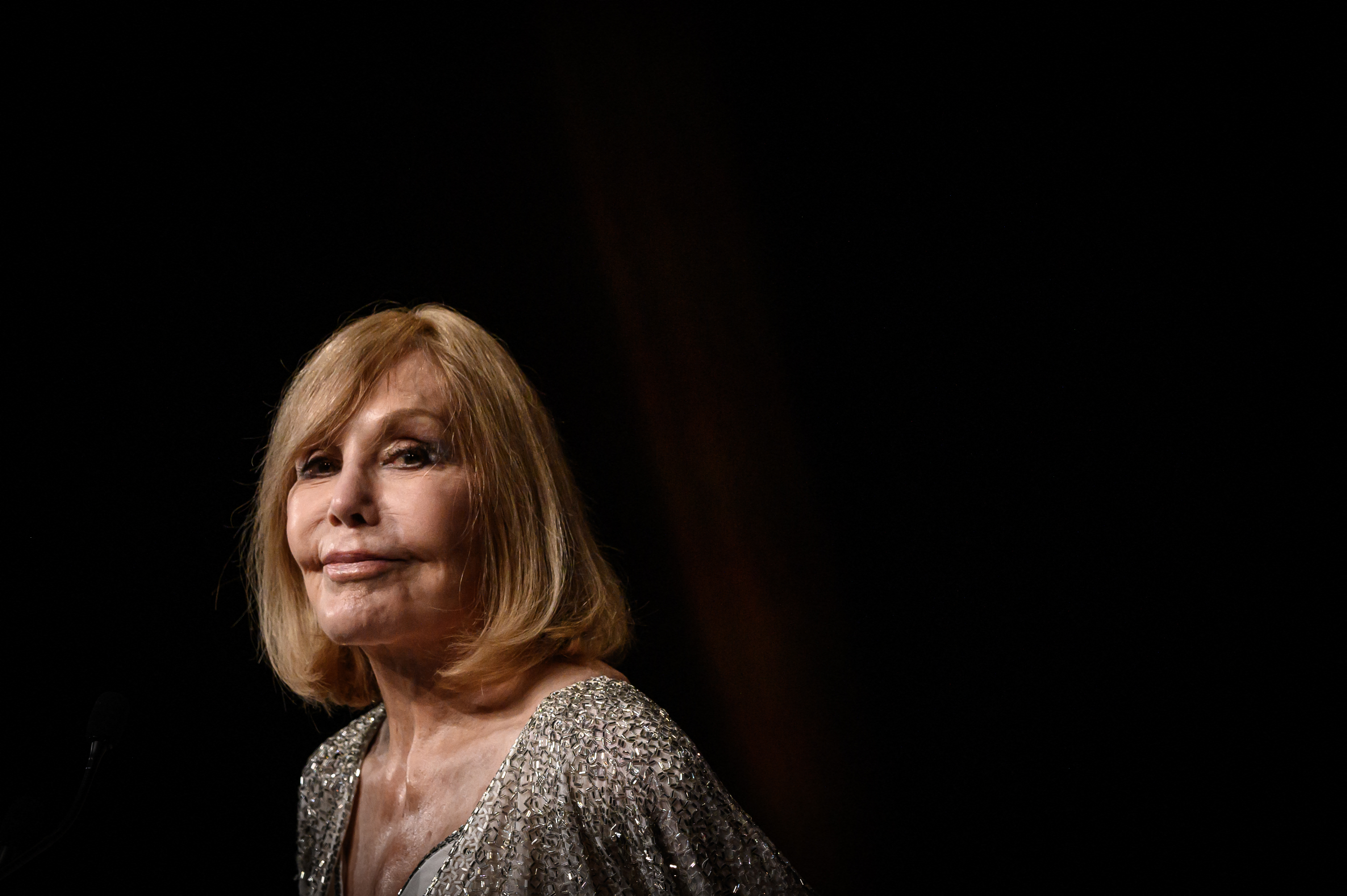 Kim Novak delivers a speech before receiving an Icon Award for her career at the 51st Deauville American Film Festival in France on September 6, 2025. She wears a silver-embellished outfit as she addresses the audience against a dark stage backdrop. | Source: Getty Images