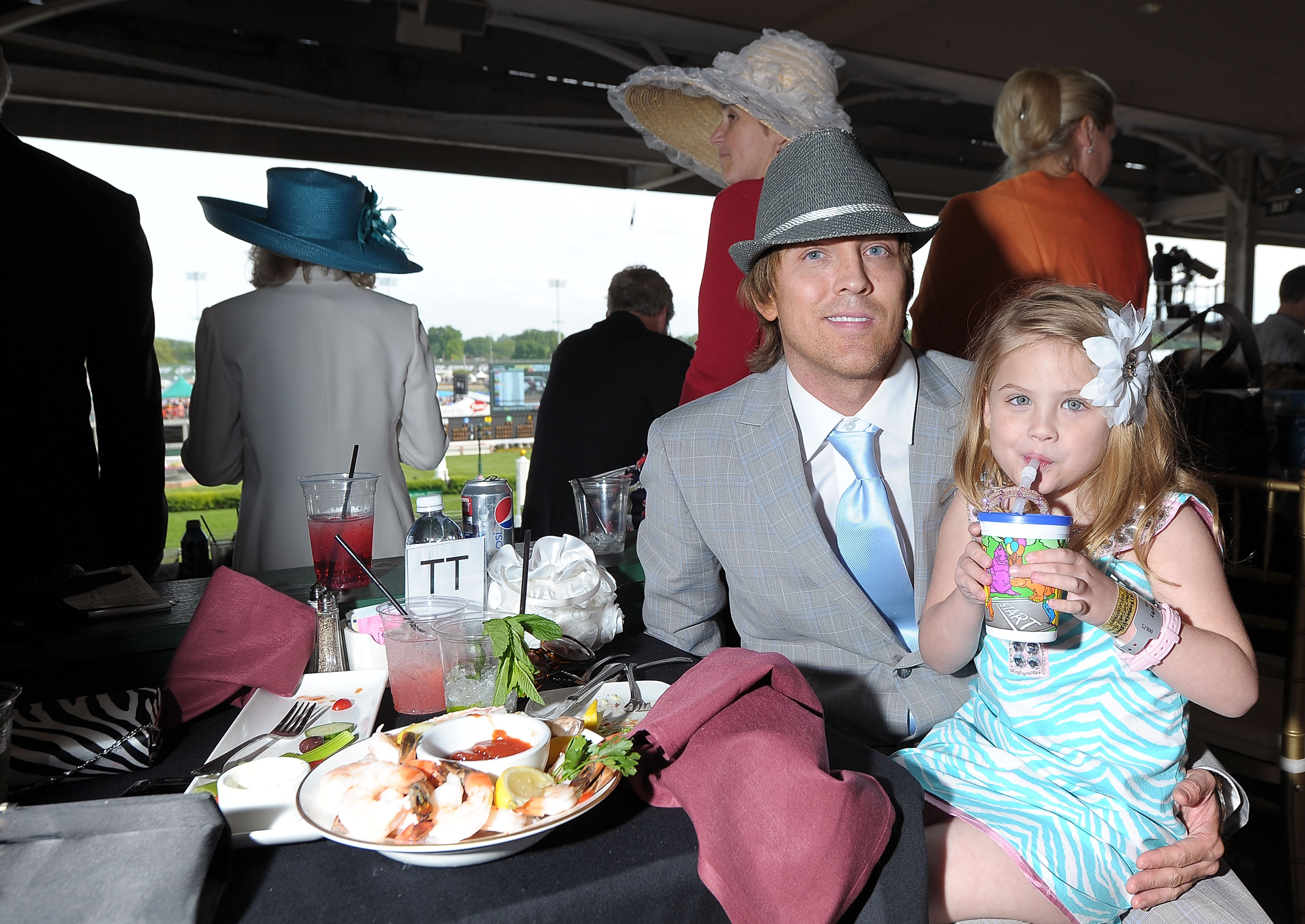 Sipping from a colorful cup through a straw, 4-year-old Dannielynn Birkhead looked right at home amid the festive pageantry of the 137th Kentucky Derby at Churchill Downs on May 7, 2011. A vibrant turquoise-and-white zebra-stripe sundress paired with a large white flower pinned neatly in her blonde hair added a delightful touch of southern charm, capturing her poised and joyful growing independence.