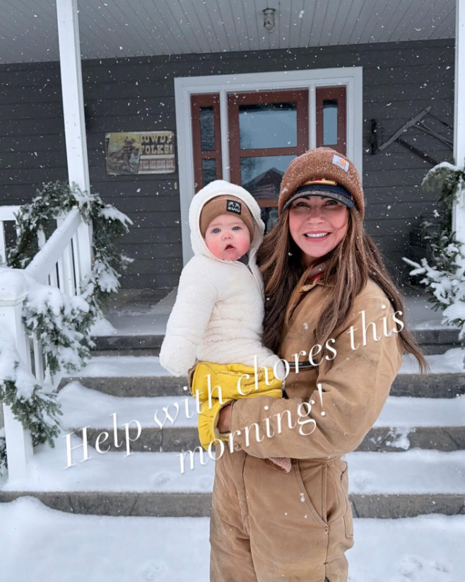 Snow covers the steps and entrance in this winter view of the family's porch. Dark siding, white railings, and a wood-trimmed front door define the exterior. | Source: Facebook/kristi.noem