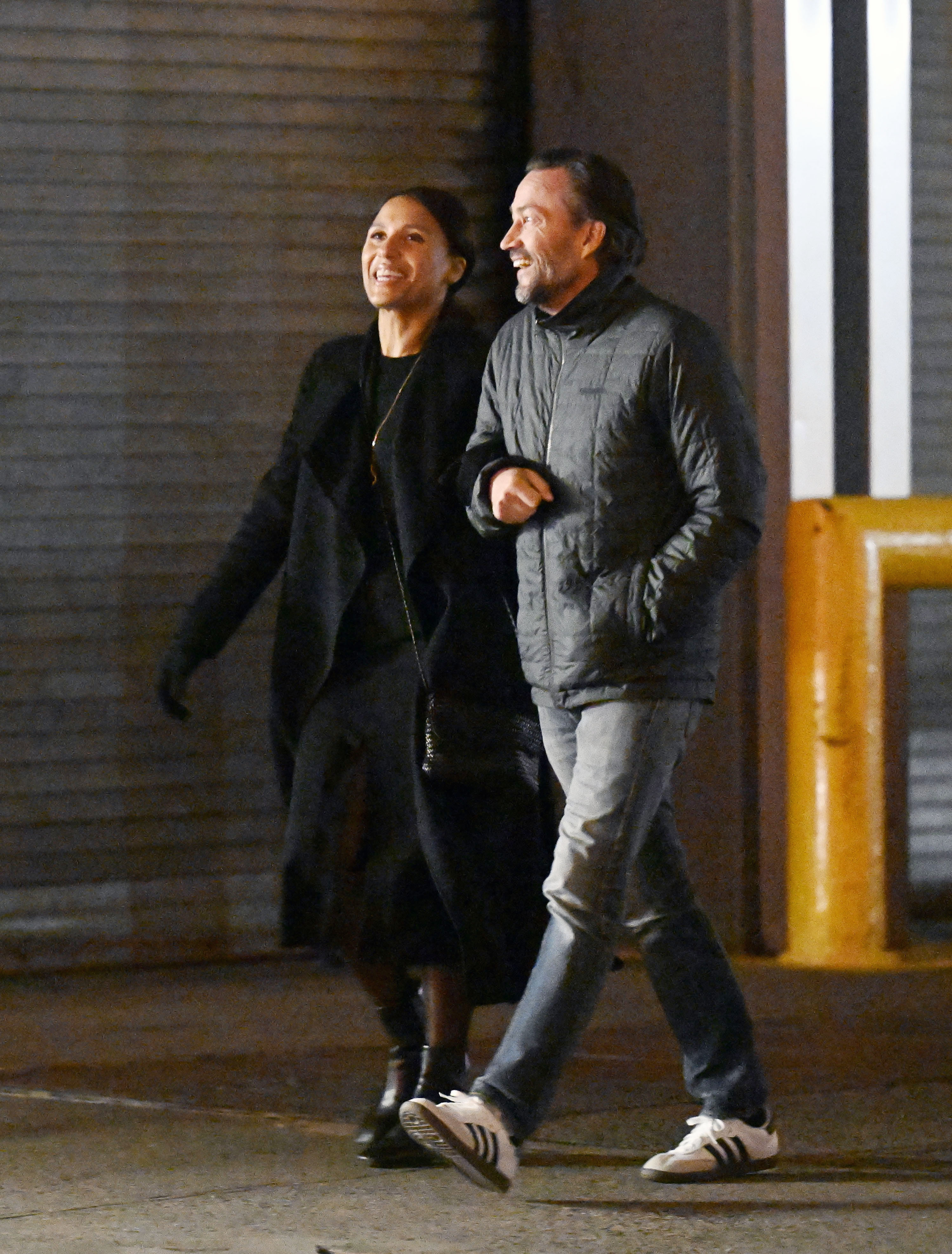 Marilee Fiebig and Andrew Shue share a laugh while walking arm in arm after dining at The Fulton in New York City on March 1, 2024. The newly public couple bundled up for the cool evening, with Fiebig dressed in a chic monochrome black outfit featuring an open trench coat, dress, leather boots, and a crossbody bag, while Shue kept it casual in a quilted grey zip-up jacket, jeans, and white Adidas sneakers. | Source: Getty Images