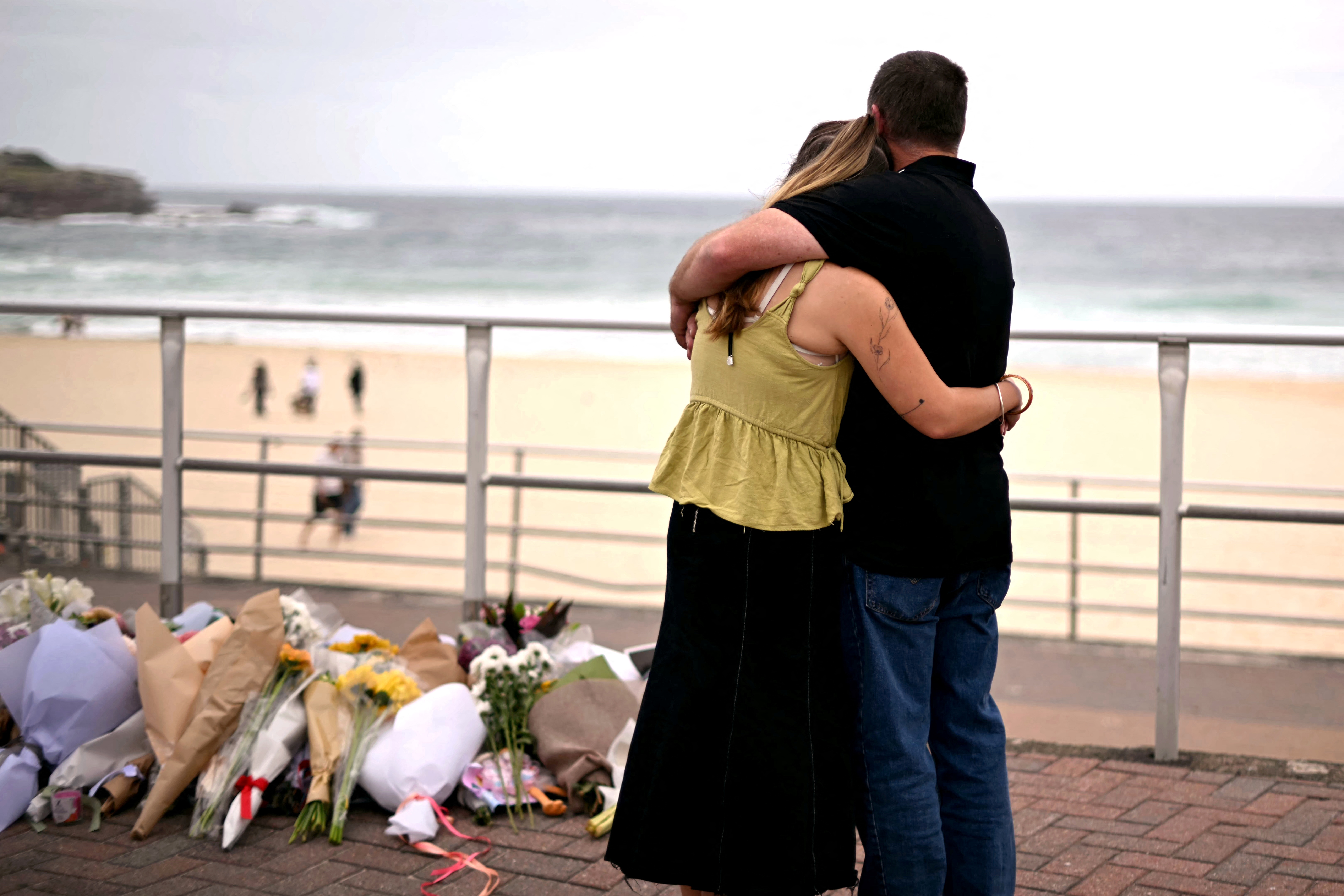 Mourners embrace near tributes piled together in memory of the victims of a shooting at Bondi Beach on December 16, 2025, in Sydney, Australia | Source: Getty Images