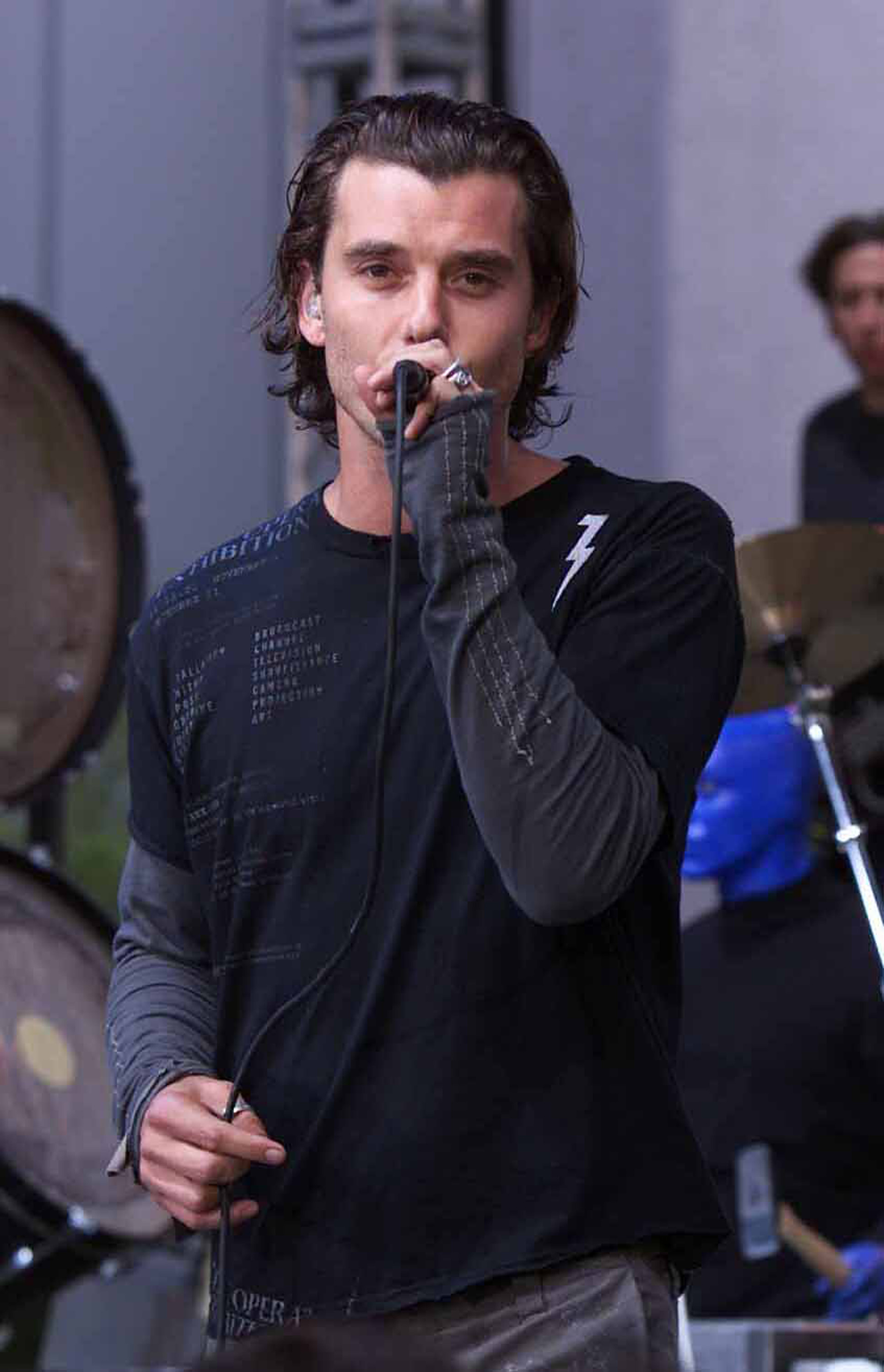 Gavin Rossdale sings into a microphone on "The Tonight Show with Jay Leno," wearing layered black and gray stagewear as Bush performs during the show's 12th season.