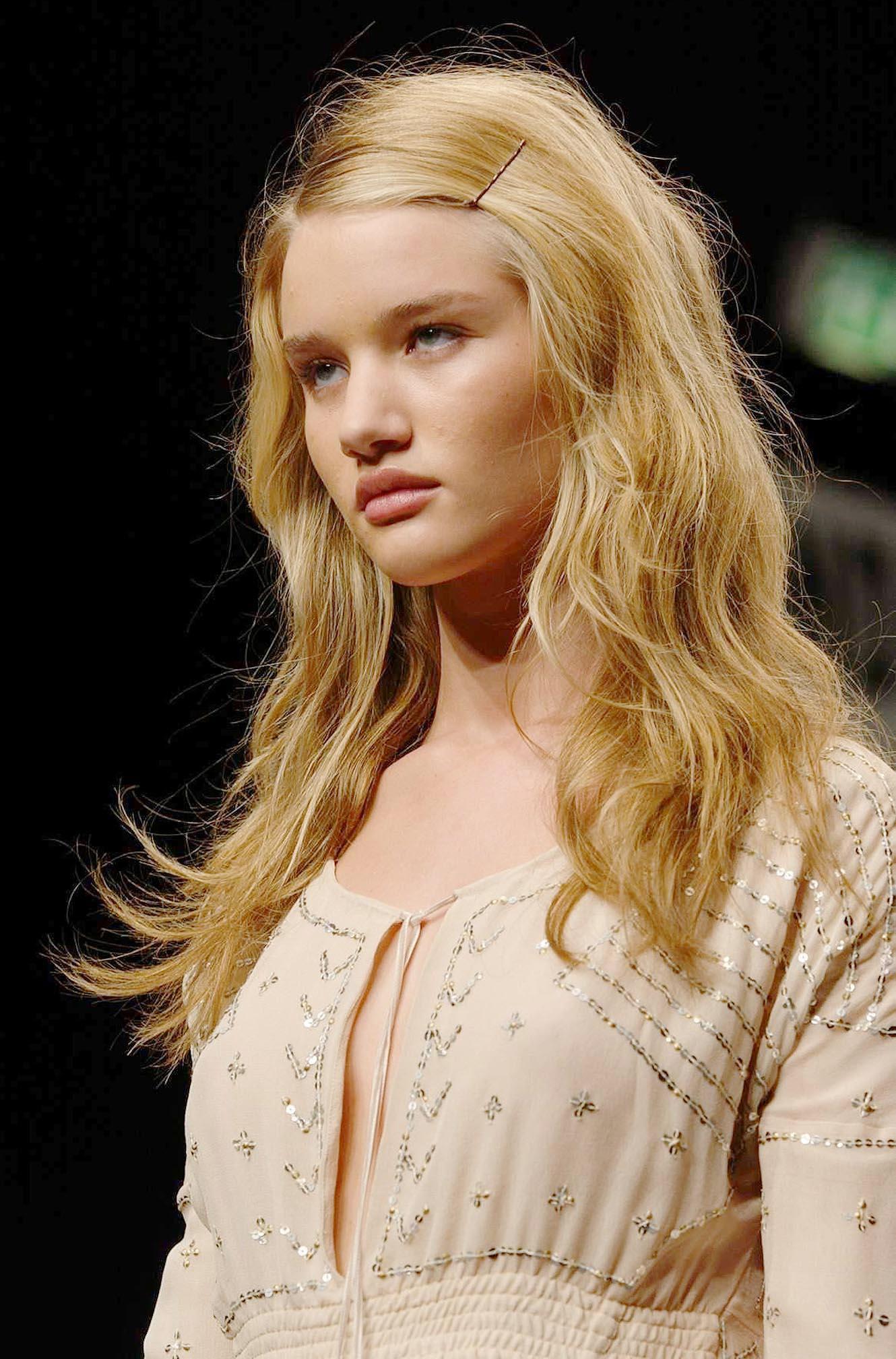 17-year-old Rosie Huntington-Whiteley walks the runway with loose blonde waves and a delicate embellished dress, showcasing her early high-fashion era. | Source: Getty Images