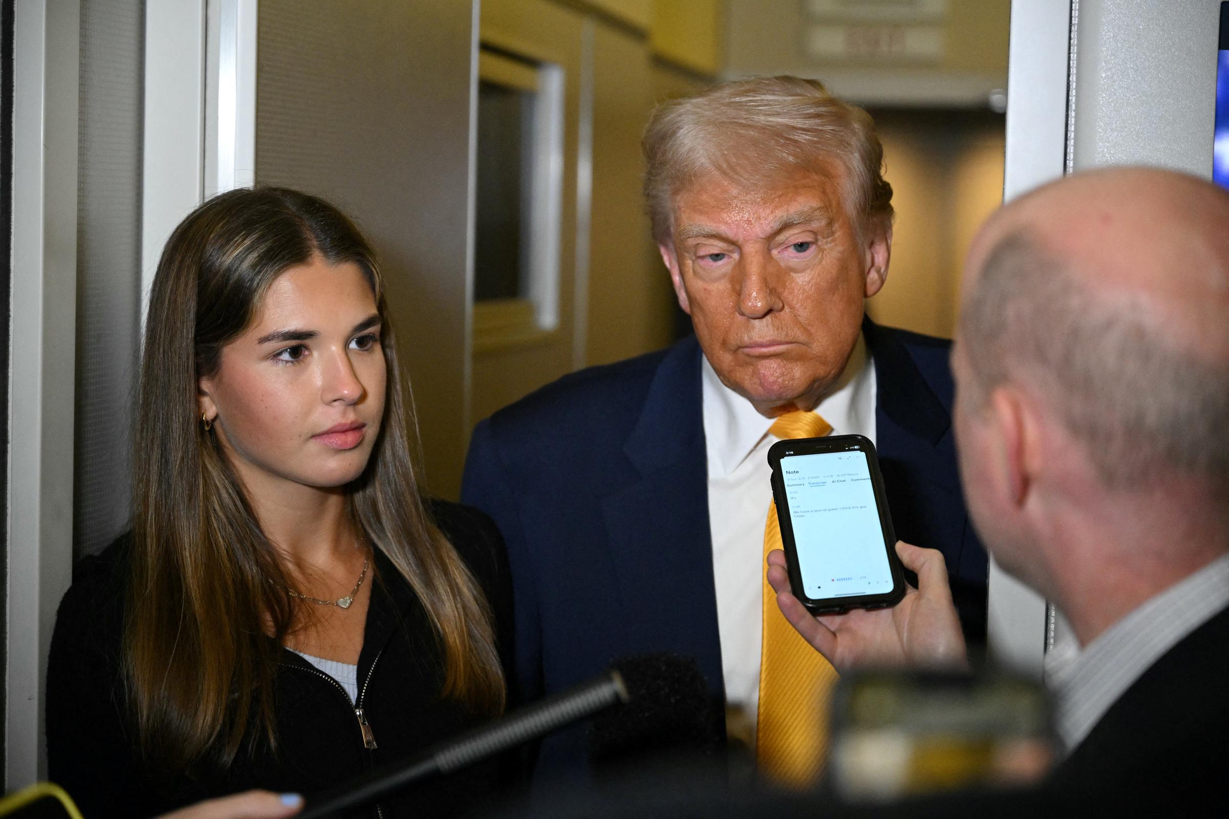 Donald Trump listens to reporters with his granddaughter Kai Madison standing beside him while flying from Miami to Palm Beach on April 13, 2025 | Source: Getty Images