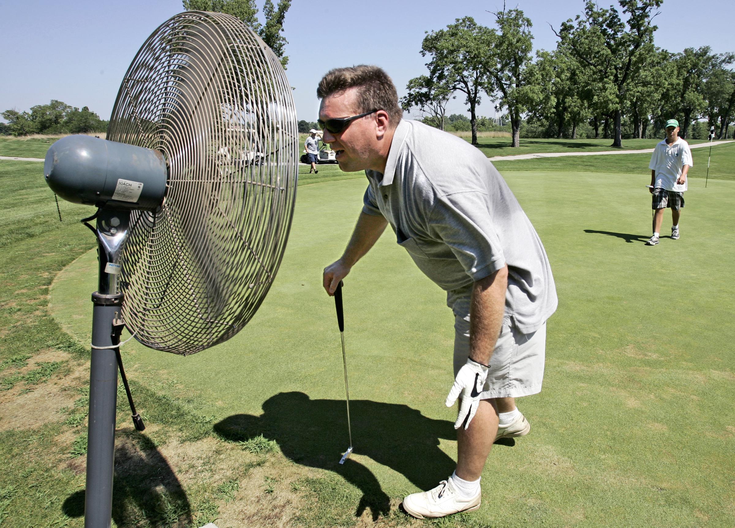 A golfer cools off in front of a fan on a hot day at Minor Park Golf Course in Kansas City, Missouri, on July 17, 2006 | Source: Getty Images
