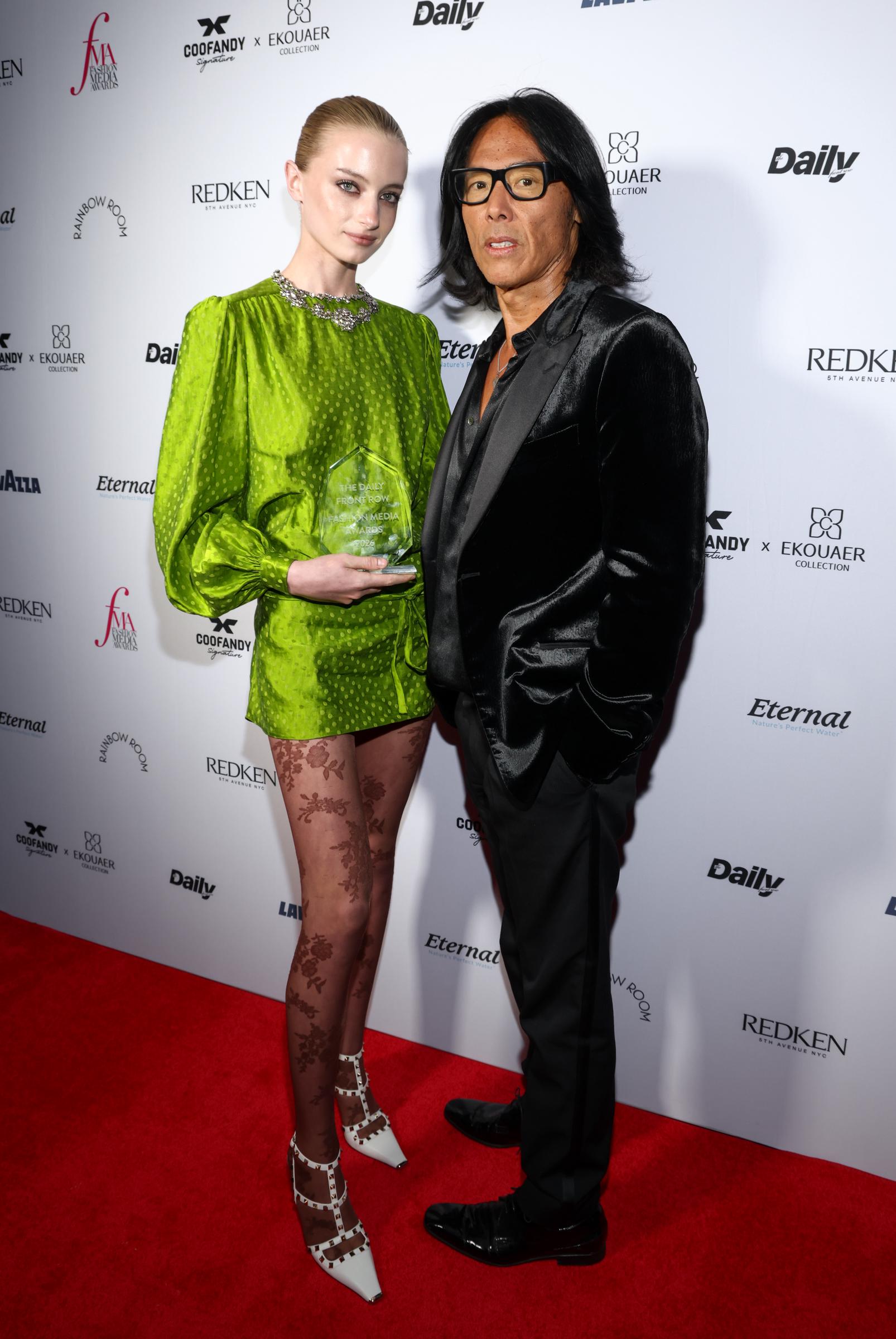 Kai Schreiber proudly held the Breakout Model of the Year trophy while posing alongside Stephen Gan at The Daily Front Row's Fashion Media Awards at the Rainbow Room on September 11, 2026, in New York City. Schreiber showcased the geometric glass honor while clad in an apple-green silk mini dress, patterned stockings, and studded white heels, as Gan stood beside the honoree dressed in a velvet black blazer, open-collar shirt, and glasses. | Source: Getty Images