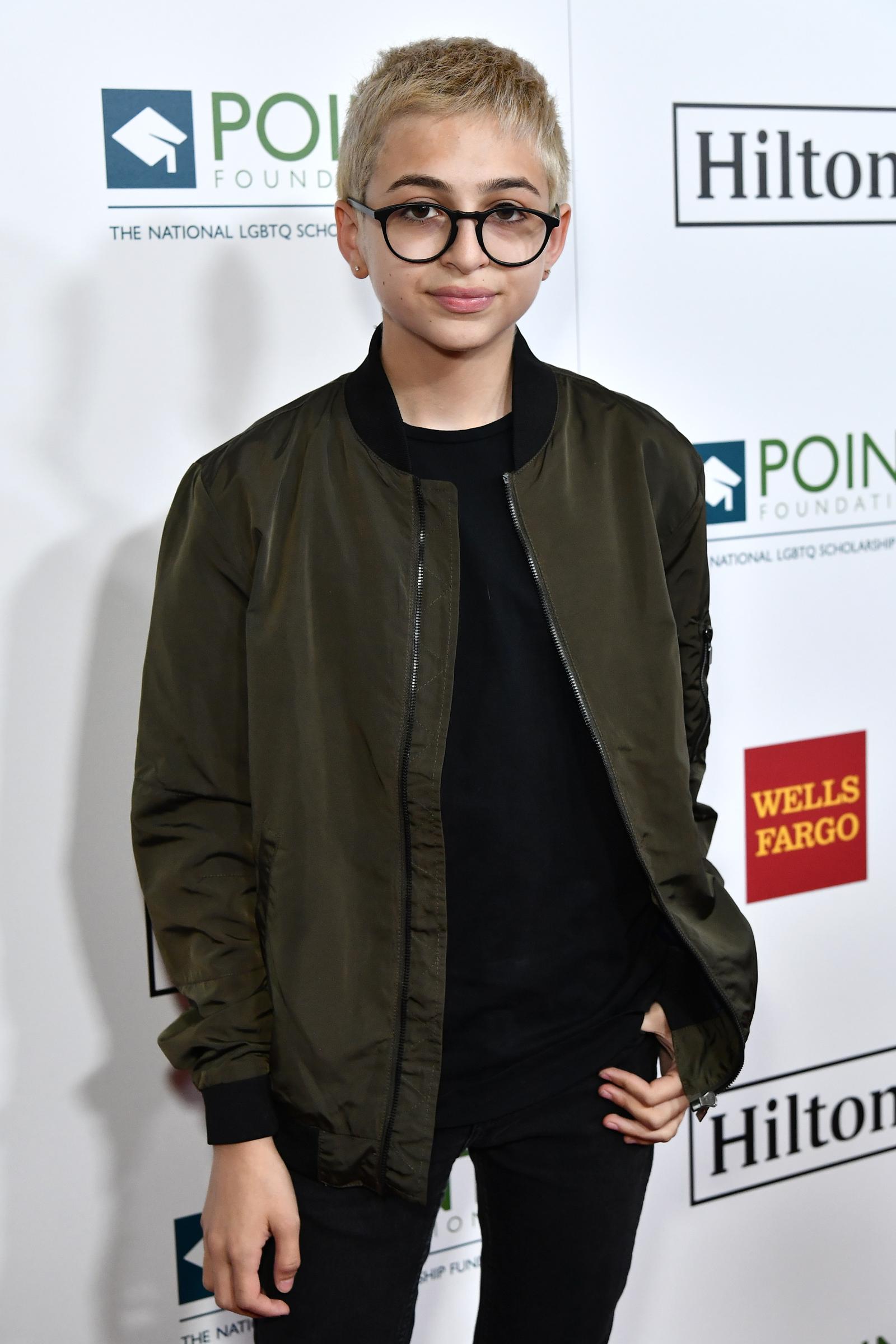 J.J. Totah attends the Point Honors Gala in Los Angeles, California, wearing a dark bomber jacket over a black shirt, black trousers, and round glasses. Totah's short, light-colored hair completes the look. | Source: Getty Images