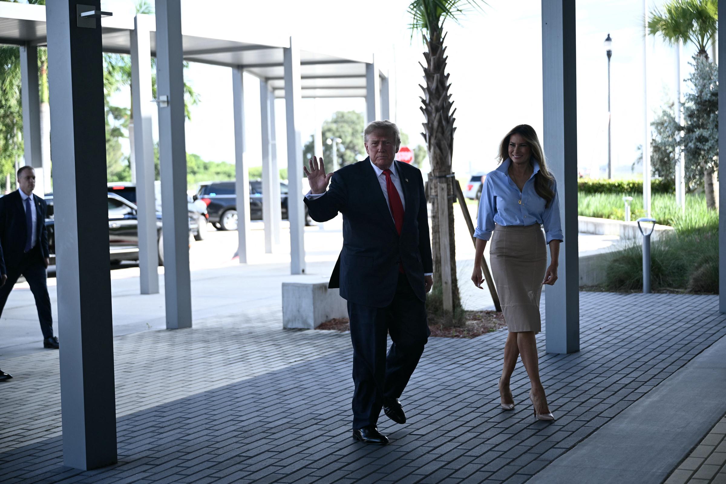 Accompanied by Donald Trump as he waves to onlookers along the sunlit outdoor breezeway, Melania showcases the clean lines of her tailored ensemble, stepping forward in towering Christian Louboutin nude pointed-toe pumps that finish the below-the-knee hemline with a needle-sharp lift.