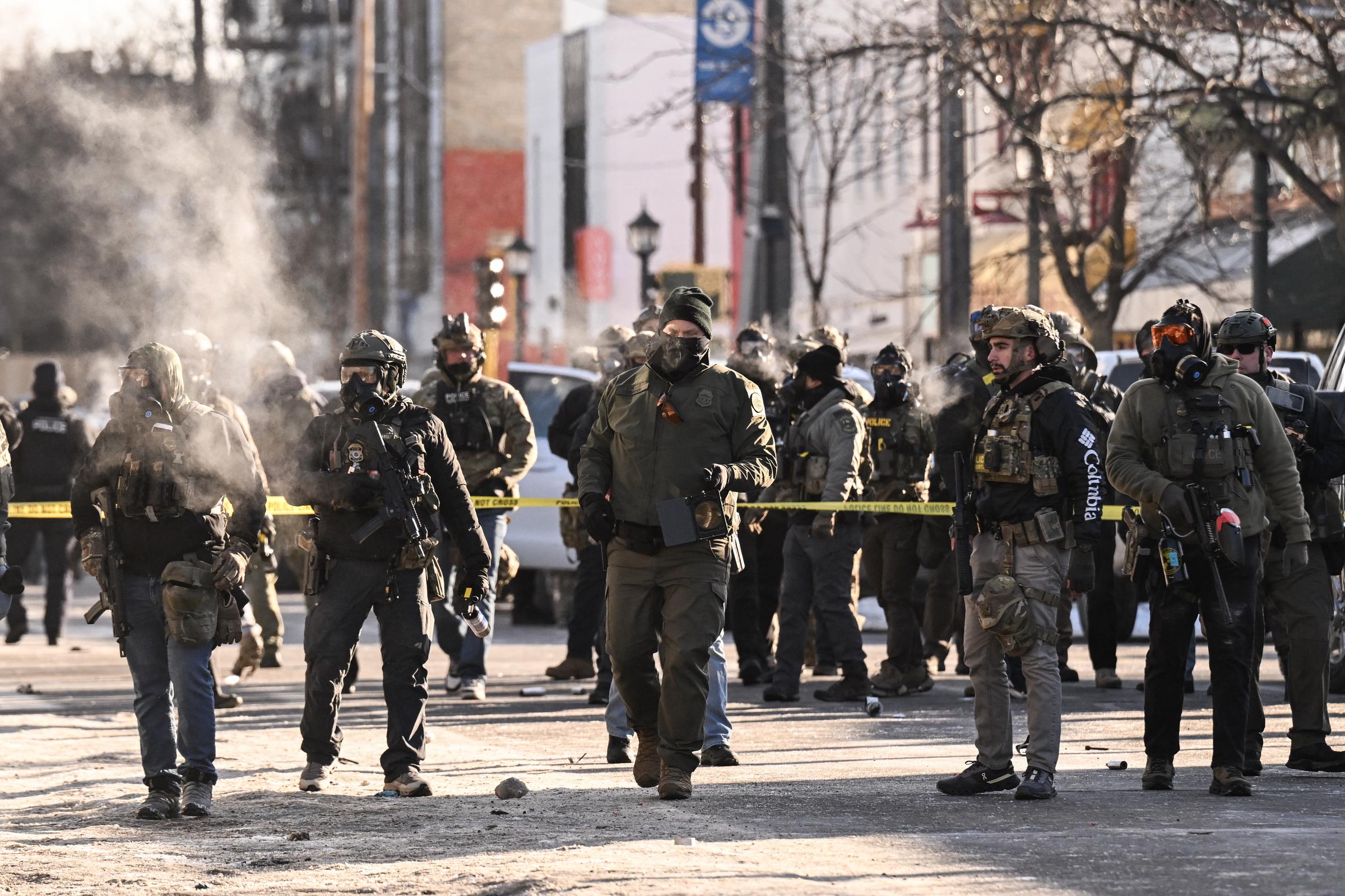 Federal agents stand behind police tape near the site of the shooting during an immigration enforcement operation. | Source: Getty Images