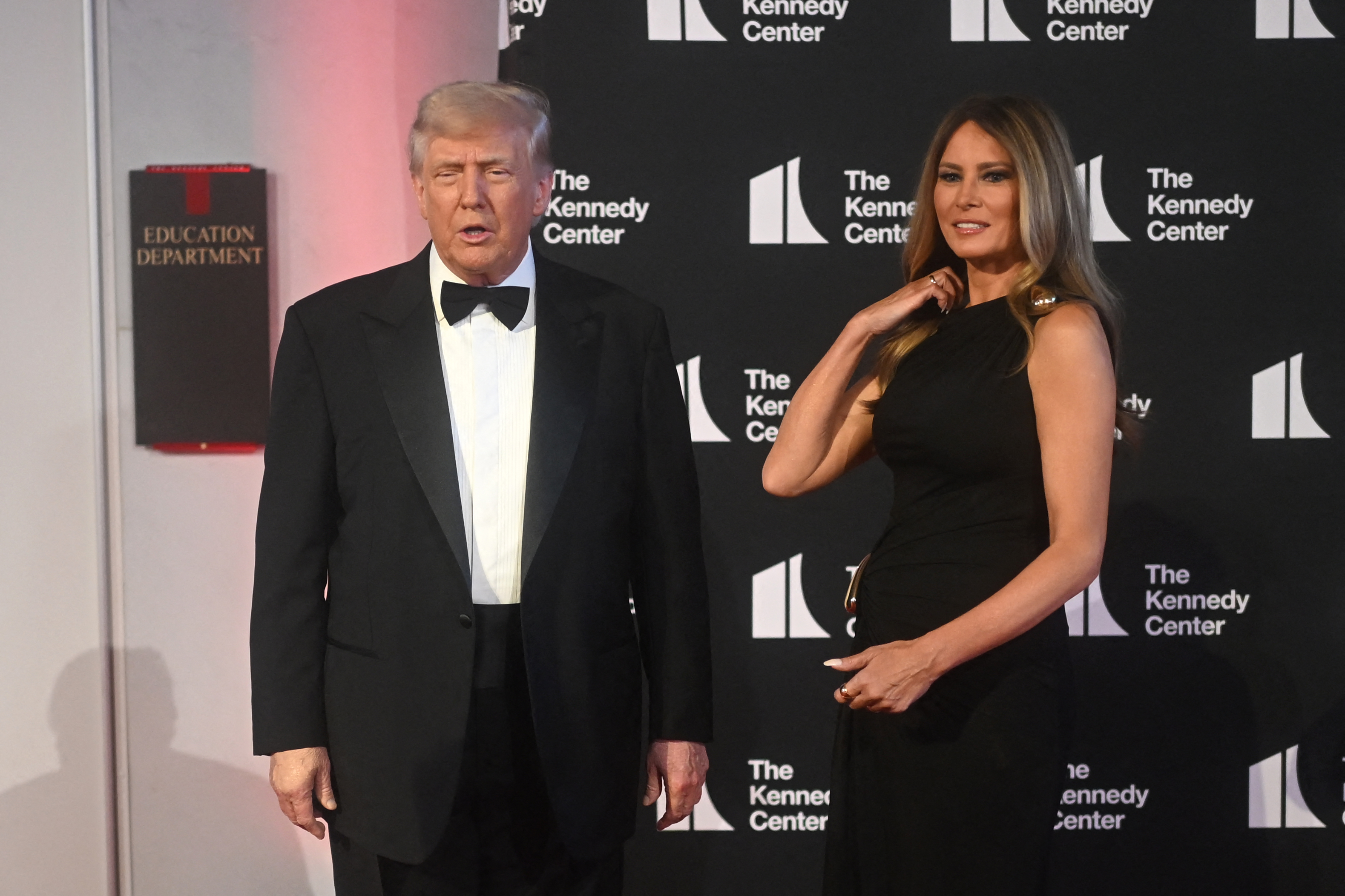 As the president looks ahead, the first lady adjusts her hair with a subtle smile during a pause for photos at the Kennedy Center's red carpet event on June 11, 2025.