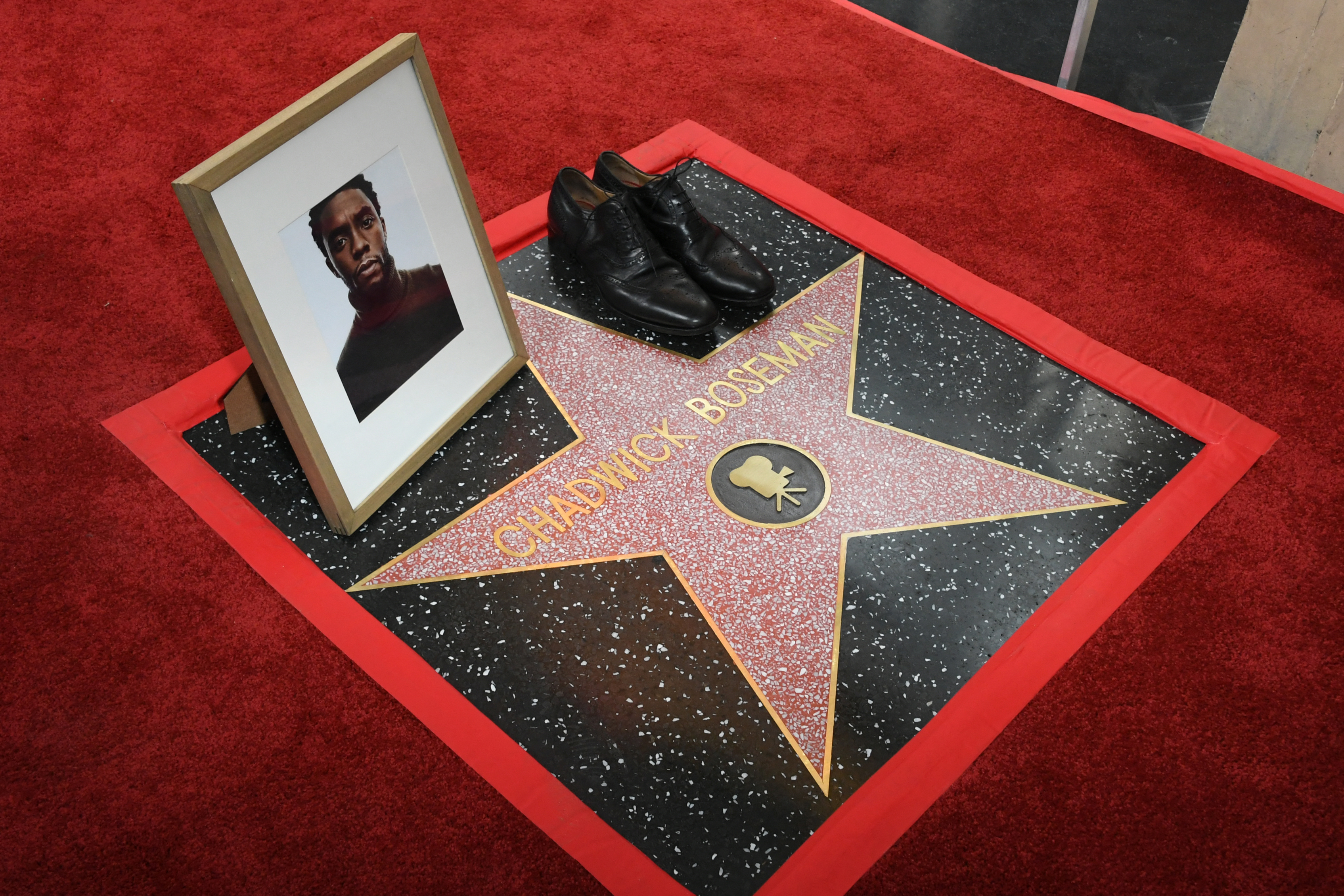 A portrait of Chadwick Boseman and a pair of shoes are placed on his star during his posthumous Hollywood Walk of Fame Star ceremony in Los Angeles, California, on November 20, 2025. | Source: Getty Images