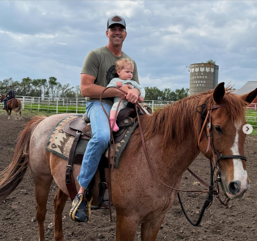 Bryon Noem sits on horseback while holding a young child in front of him. | Source: Instagram/kristinoem