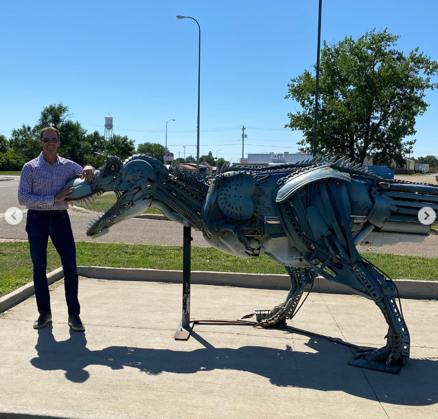 With a grin, he poses beside a striking metal sculpture—part roadside art, part mechanical marvel. | Source: Instagram/sdbryonnoem