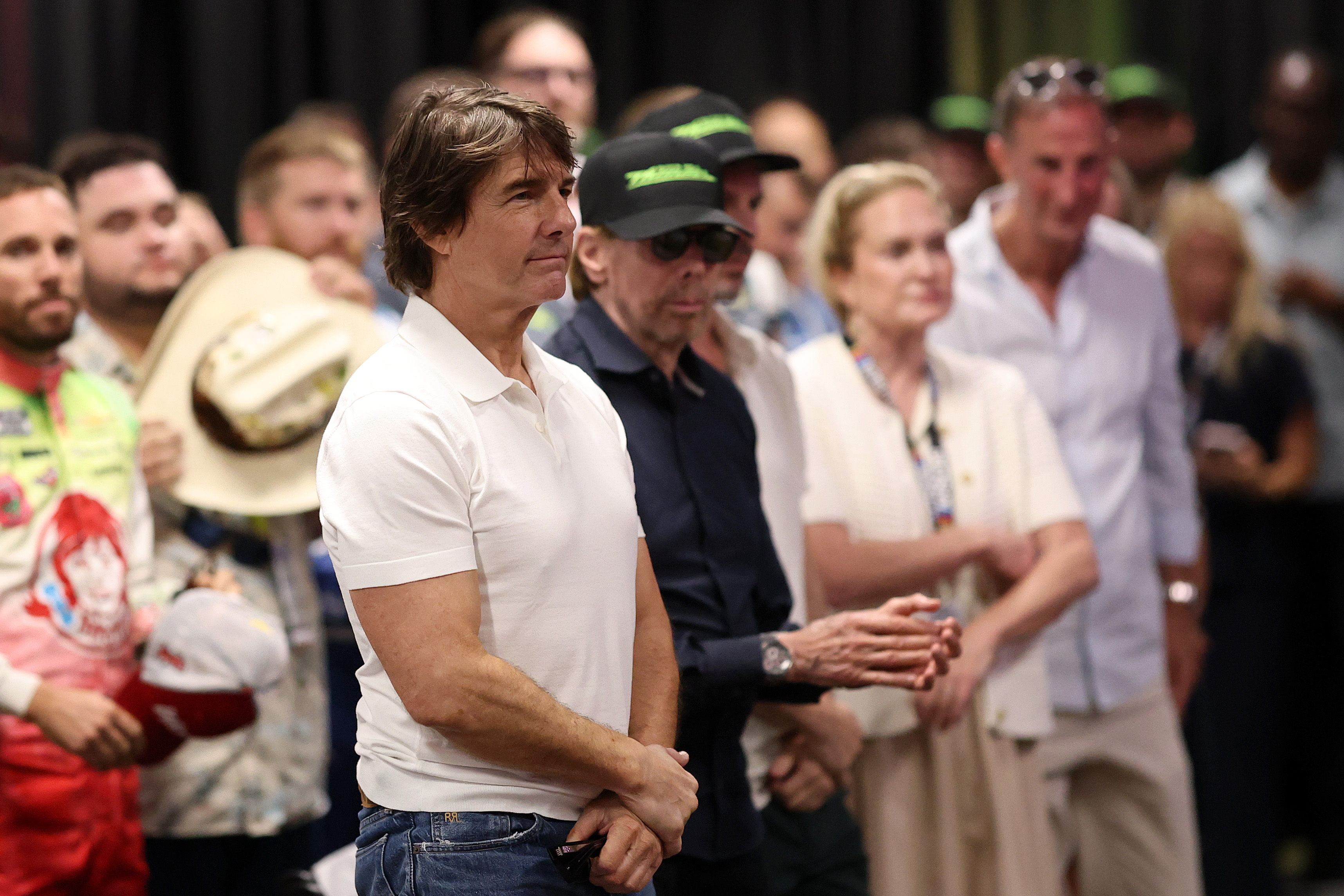 Cruise stands among attendees during the pre-race drivers' meeting at Daytona International Speedway. The photo captures him with a more neutral expression, providing a different view from the smiling conversational image taken at the same gathering. | Source: Getty Images