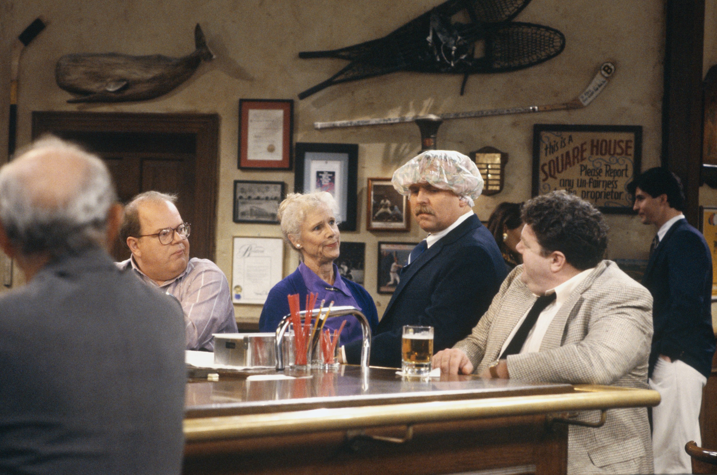 George Wendt appears as Norm Peterson in the 1982 "Cheers" episode "Ma's Little Maggie" alongside Paul Willson, Frances Sternhagen, and John Ratzenberger | Source: Getty Images