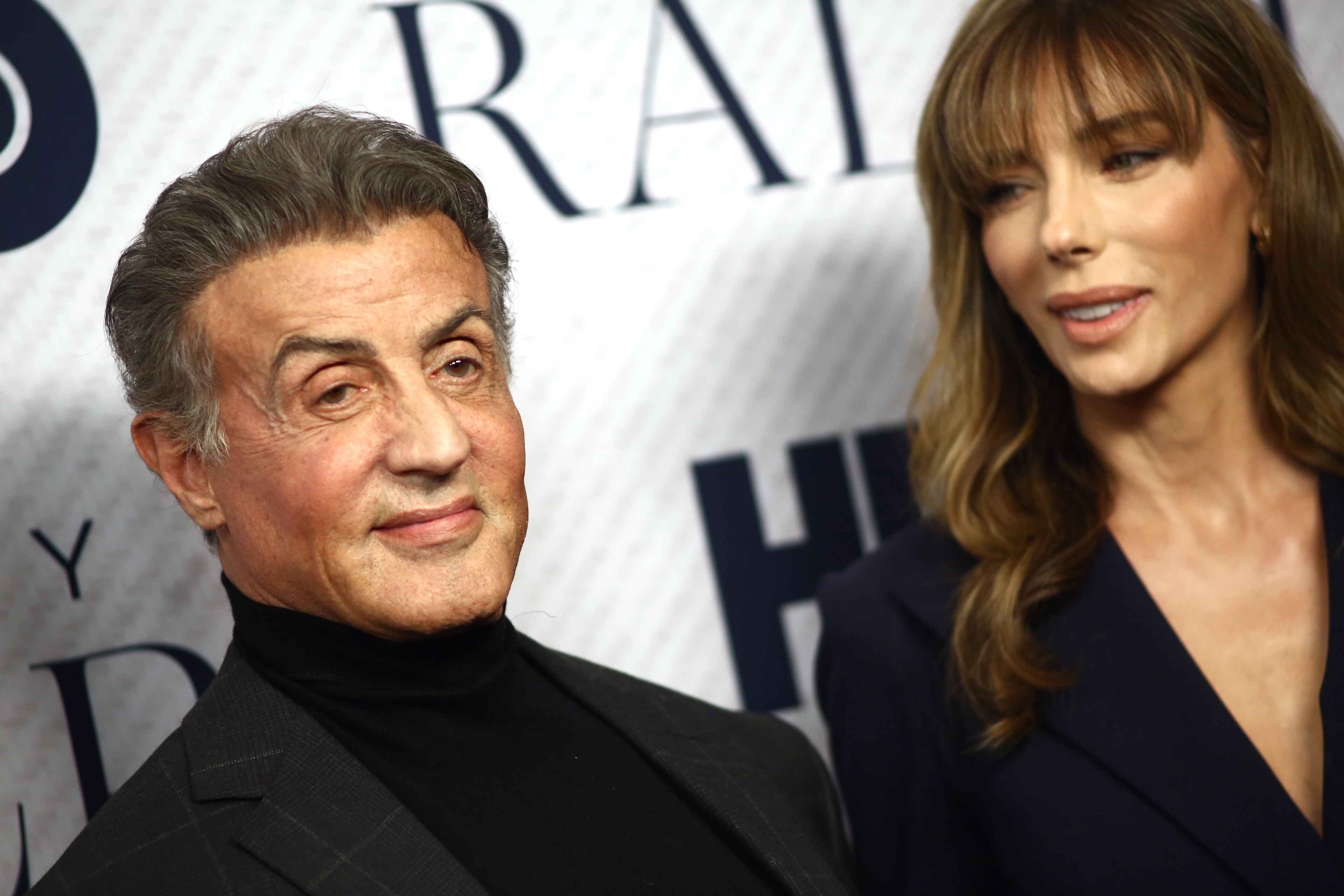 Sylvester Stallone and Jennifer Flavin attended the premiere of the HBO documentary film "Very Ralph" at The Paley Center for Media in Beverly Hills, California, on November 11, 2019. Photographed against the event backdrop, Stallone wore a dark jacket over a black turtleneck, while Flavin appeared beside him in a navy ensemble. The occasion marked another public outing for the pair, who had been married for more than two decades.