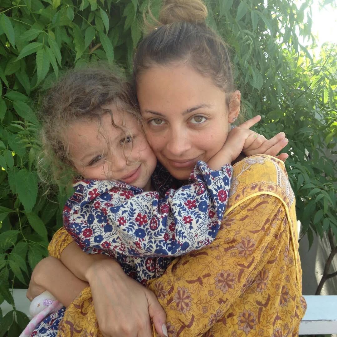 Nicole Richie hugs Harlow Winter Kate Madden tightly in an outdoor portrait framed by greenery. Wearing patterned clothing, mother and daughter press their faces together in a warm snapshot from Kate's childhood. | Source: Instagram/nicolerichie and joelmadden